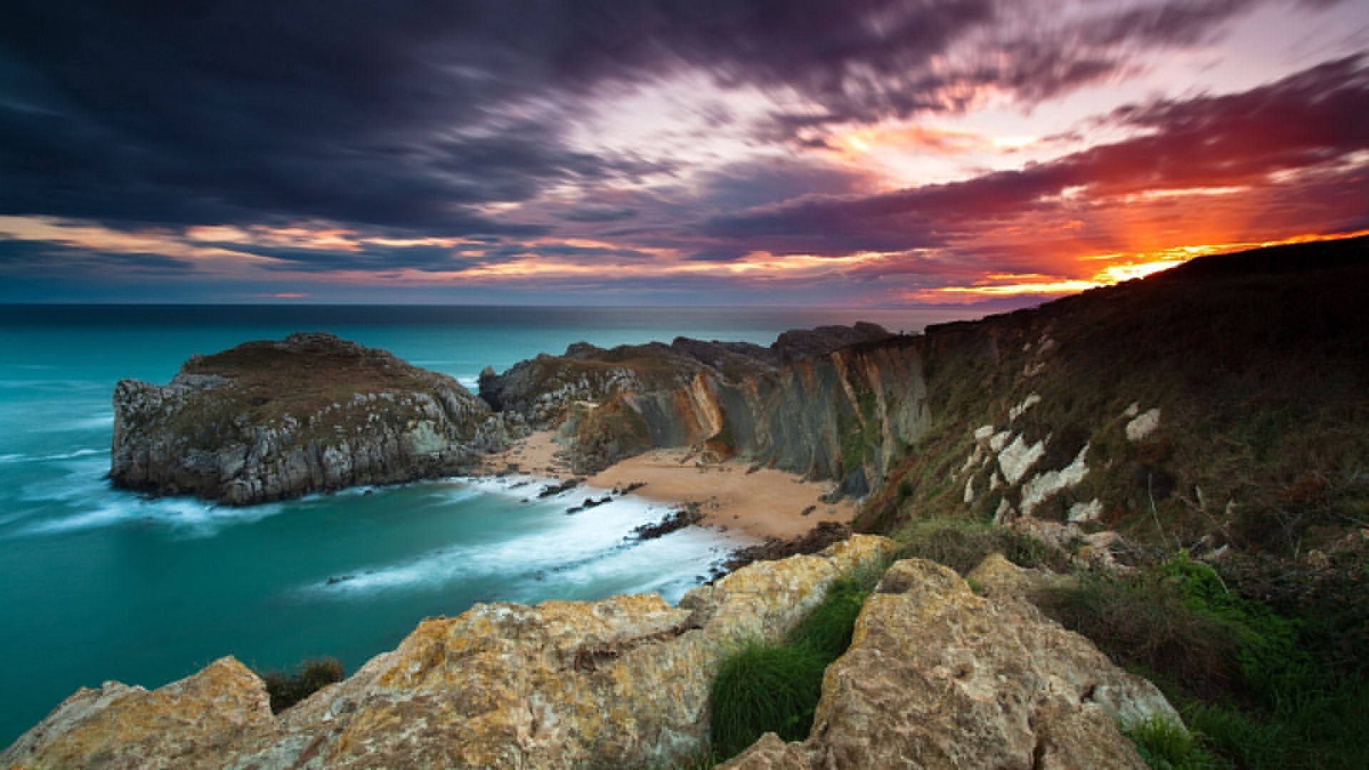 Dramatic sunset over a rocky coastline and ocean HD Wallpaper