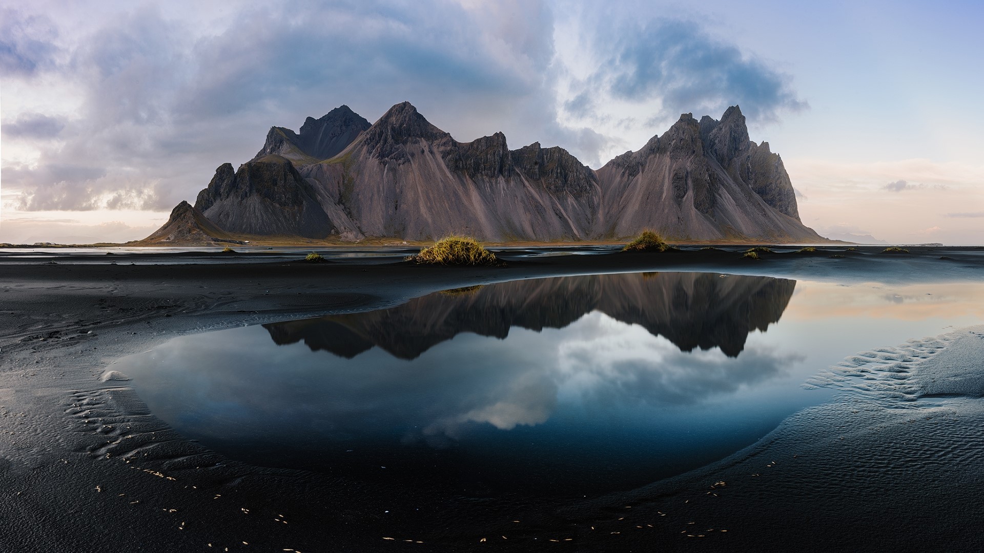 Mountains reflected in a tidal pool on black sand beach HD Wallpaper