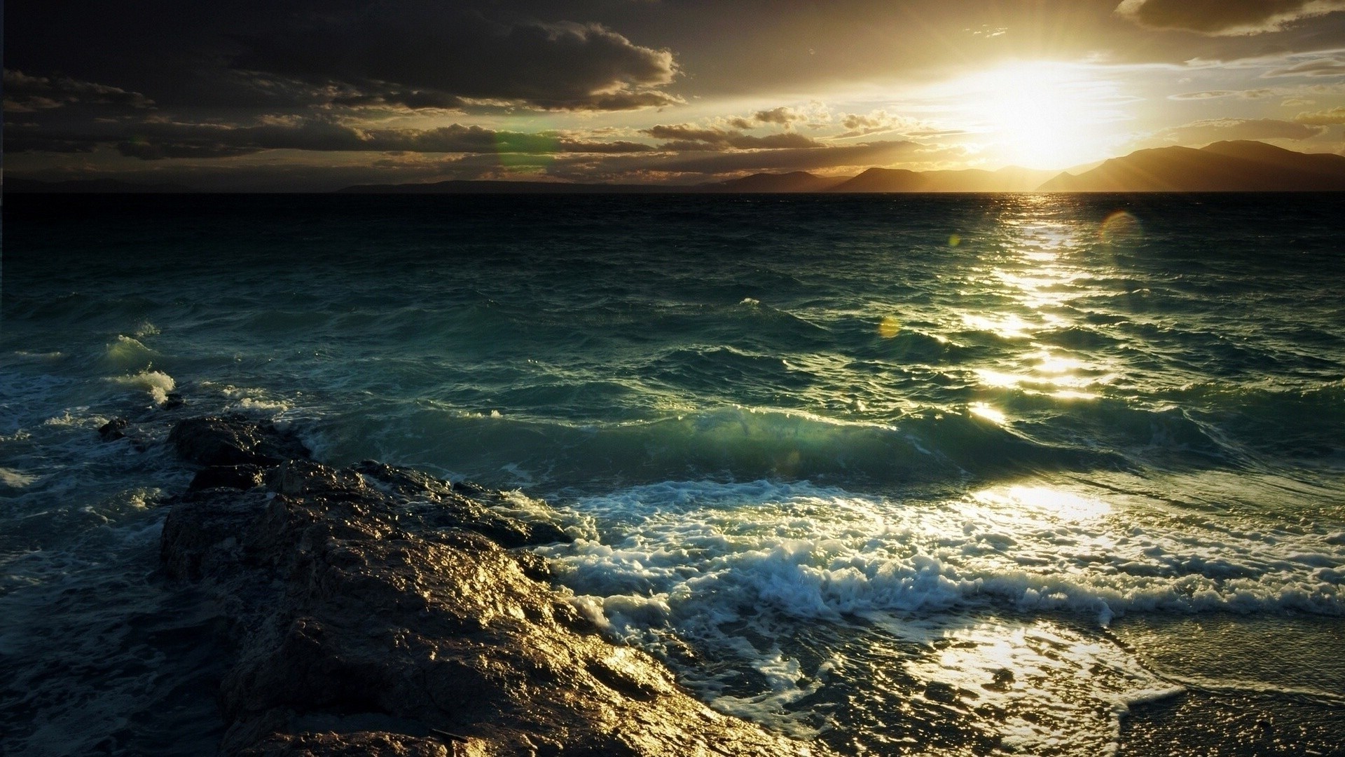 Ocean waves crashing on rocky shore at sunset HD Wallpaper