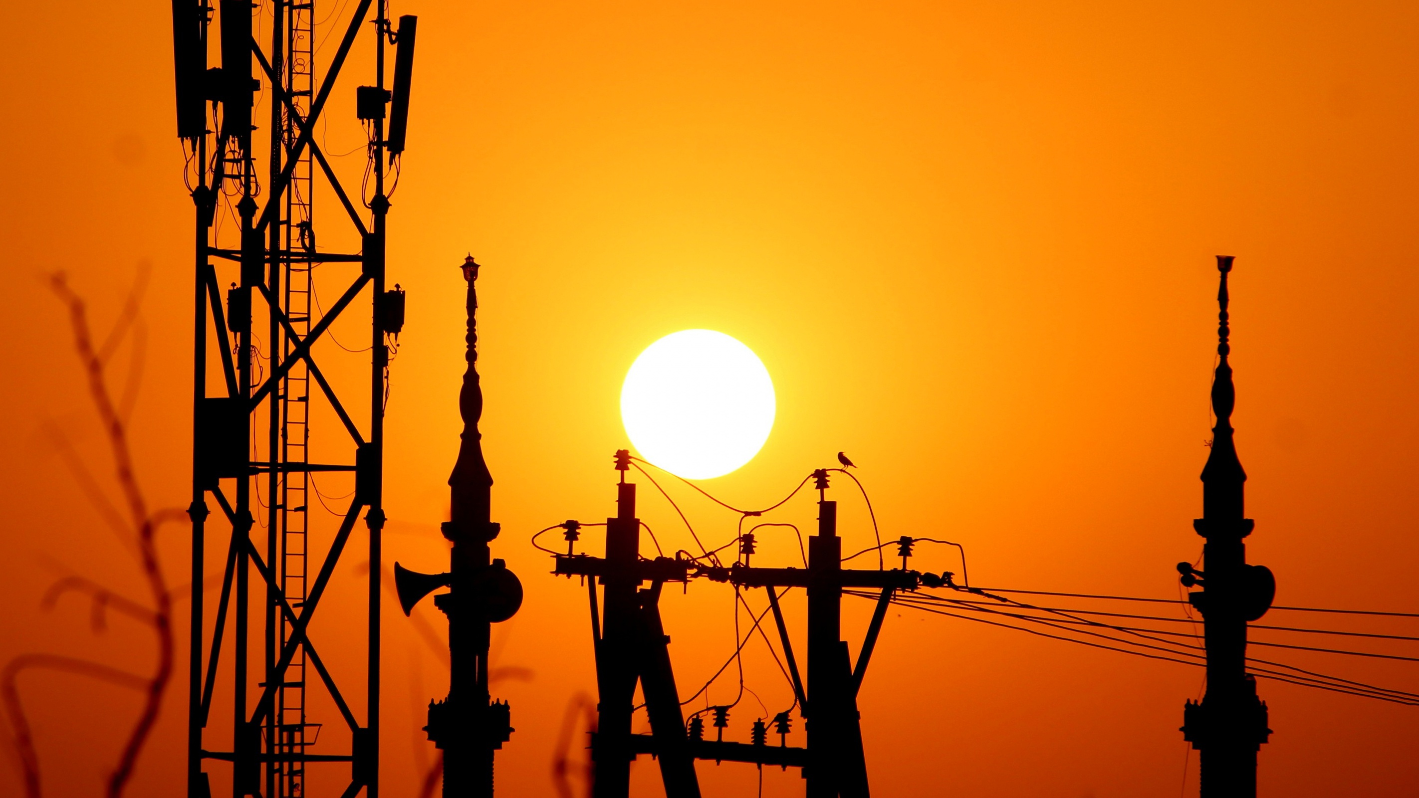 Silhouette of cell towers and power lines against a sunset HD Wallpaper