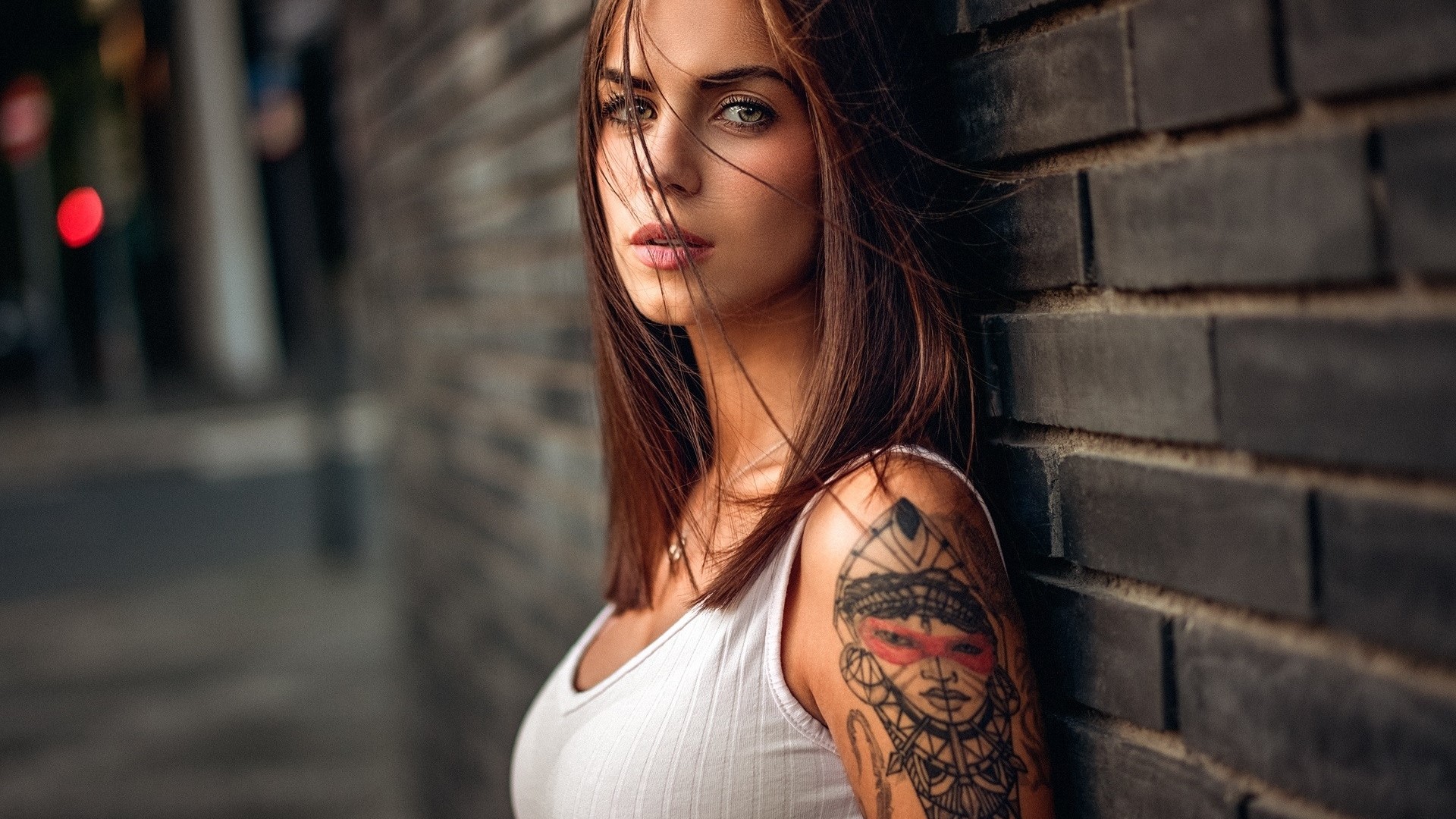Woman with tattoo leaning against brick wall HD Wallpaper