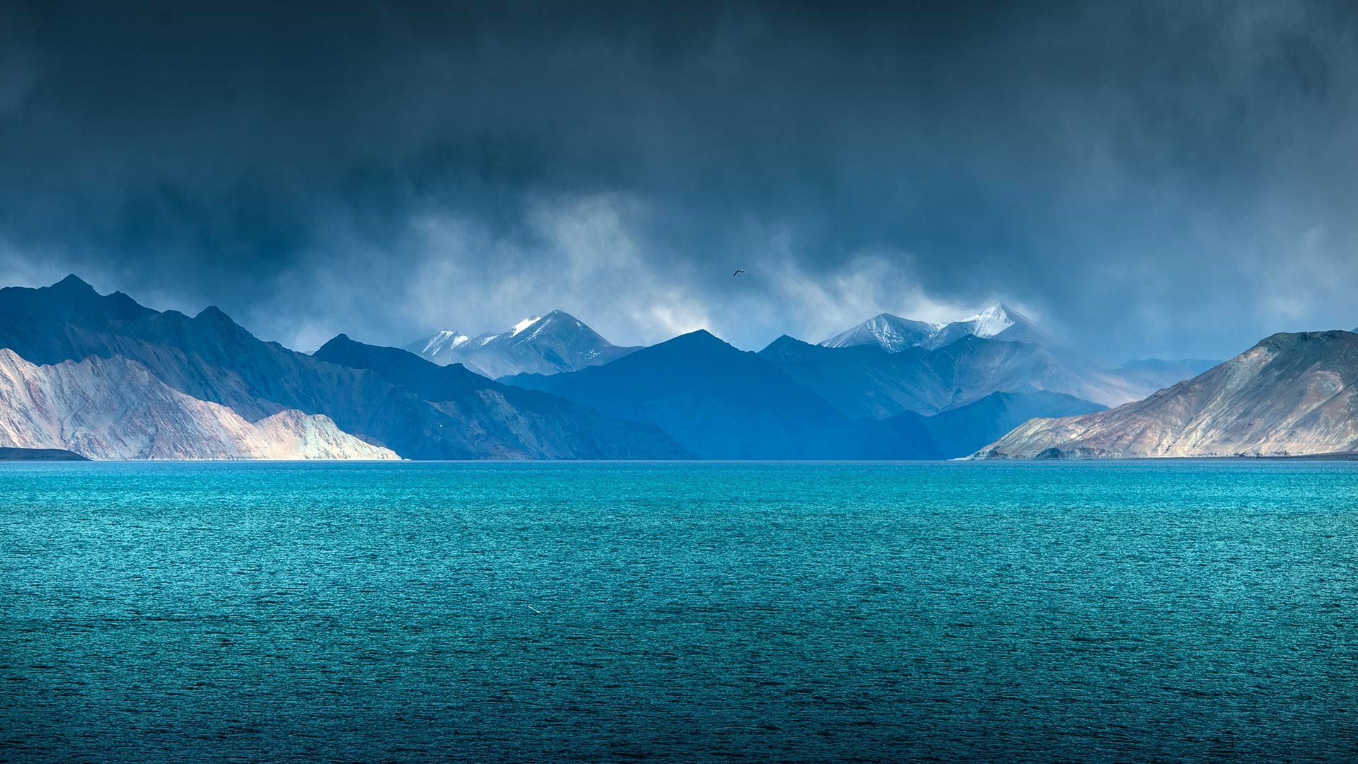 Turquoise lake and mountains under stormy sky HD Wallpaper