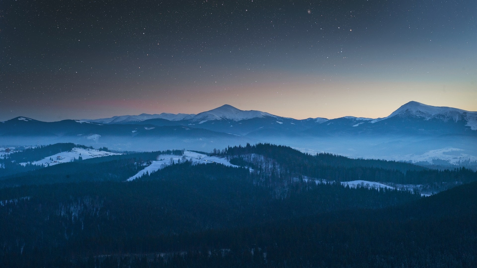 Snowy mountains under a starry night sky with mist HD Wallpaper