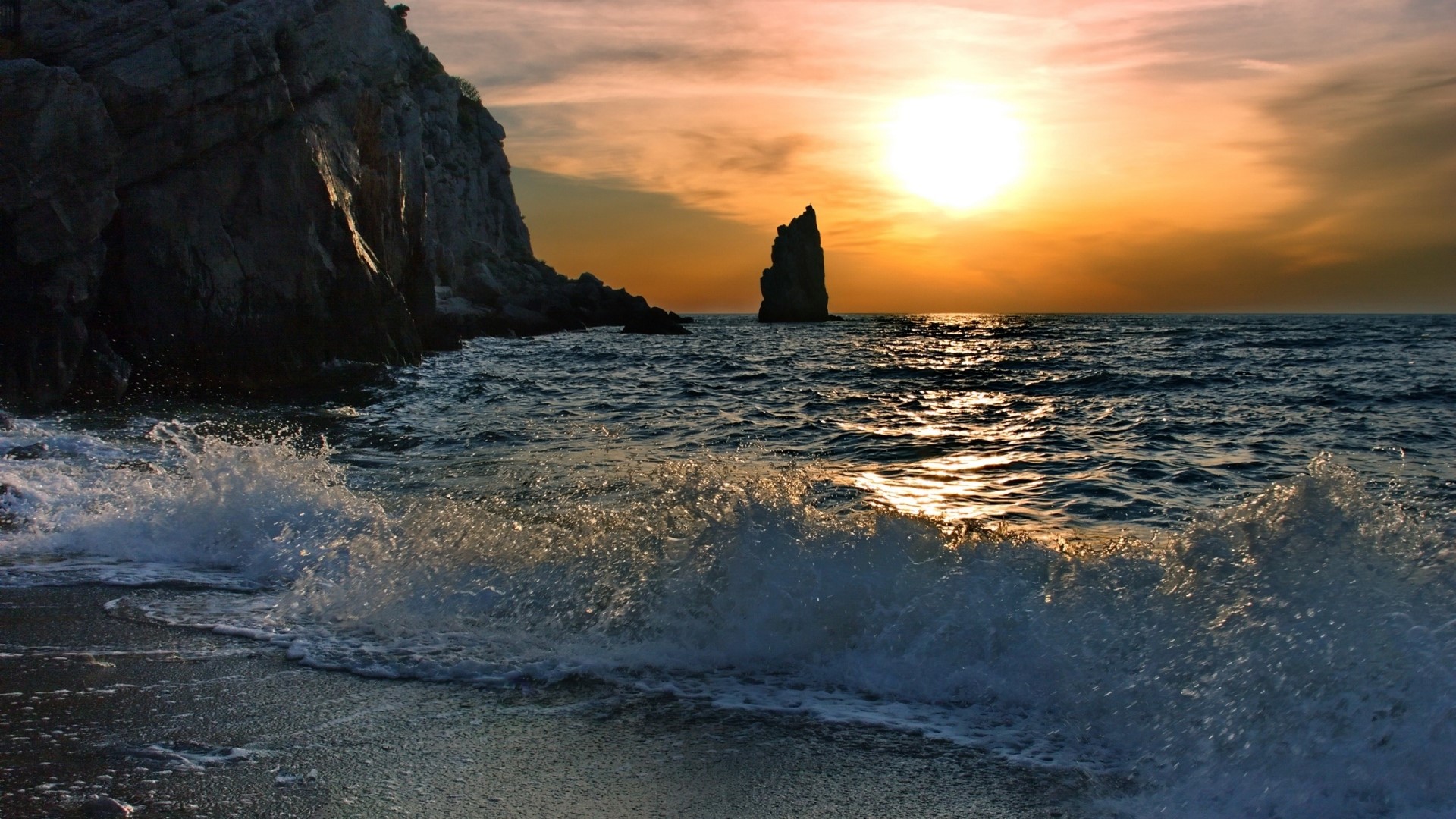 Ocean waves crash on a rocky coast at sunset HD Wallpaper