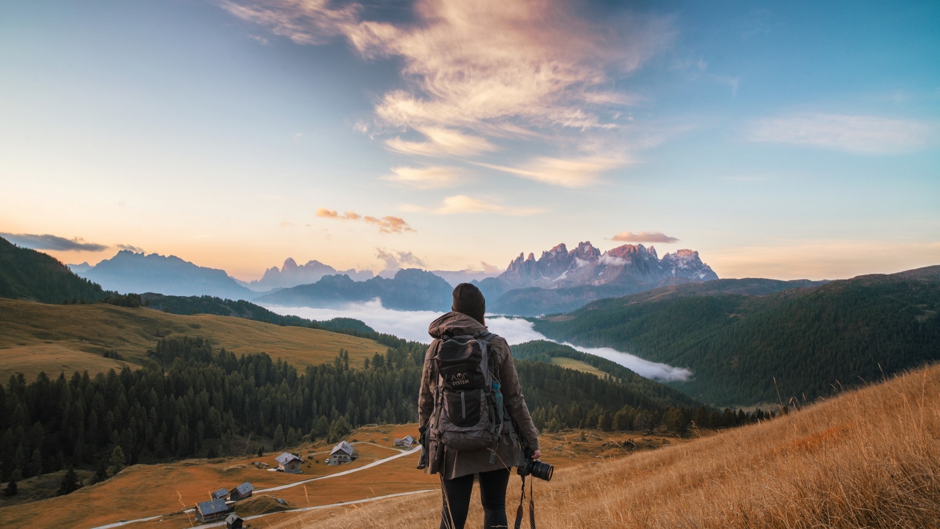 Woman with backpack and camera in mountains HD Wallpaper