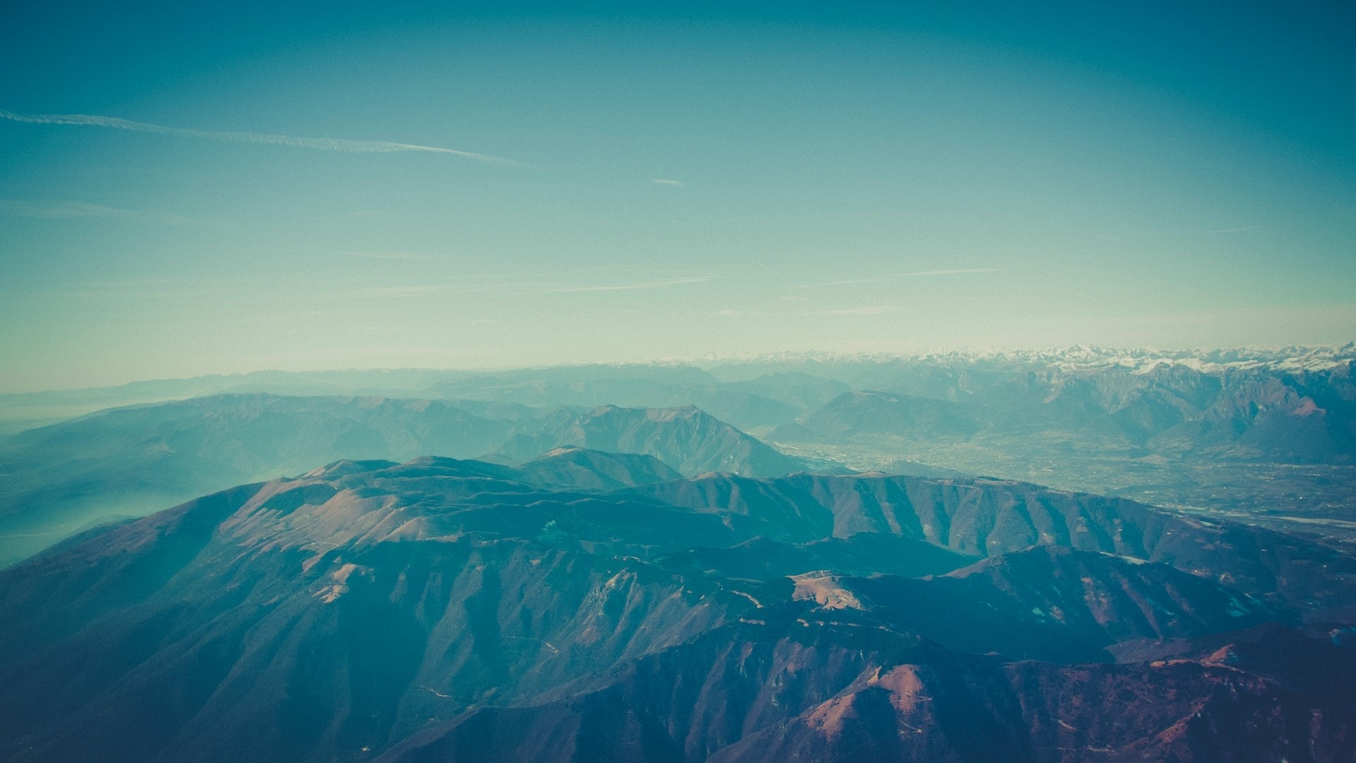 Aerial view of mountain ranges under a clear blue sky HD Wallpaper