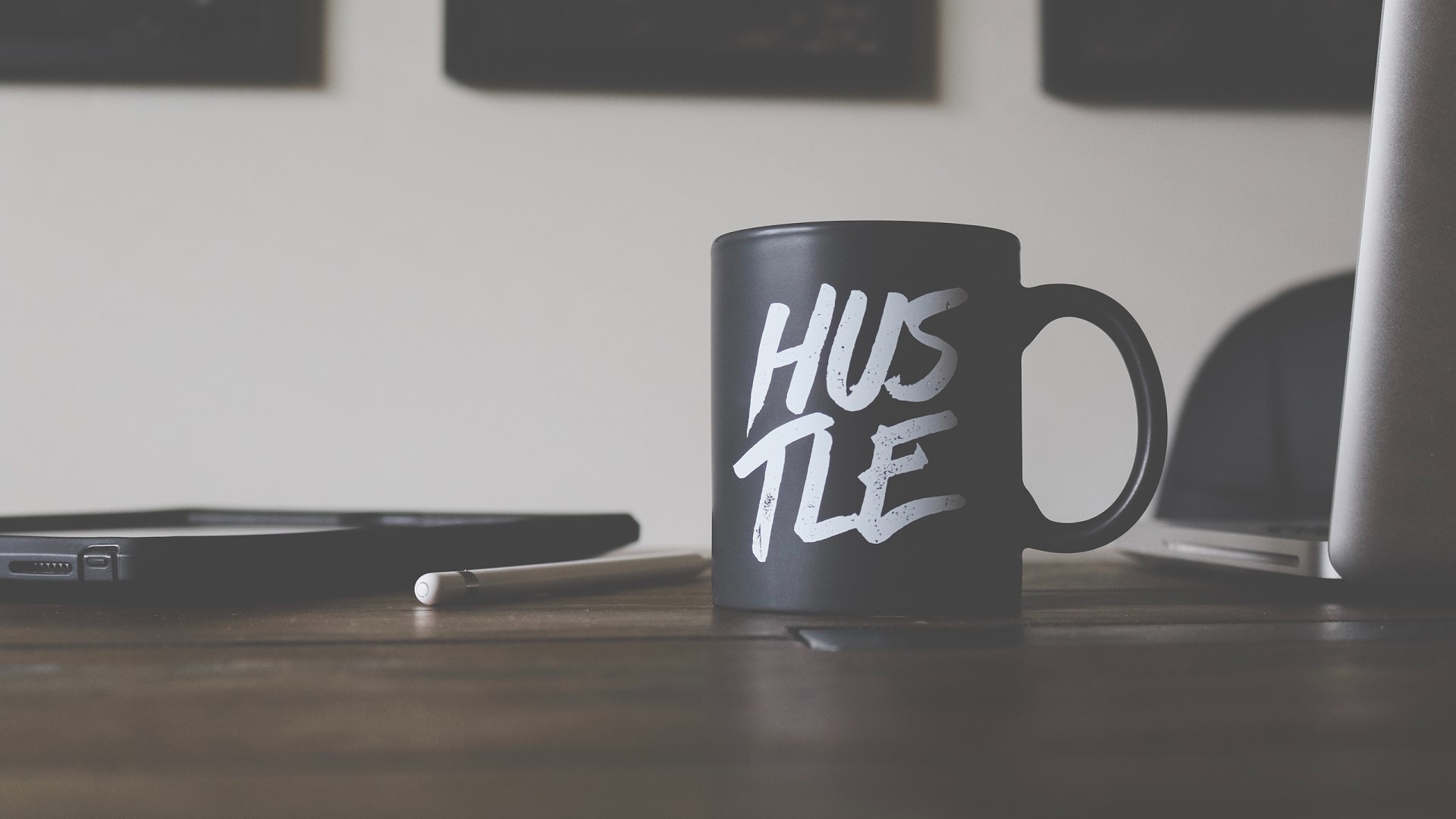 Black mug with "Hustle" text on a wooden table HD Wallpaper