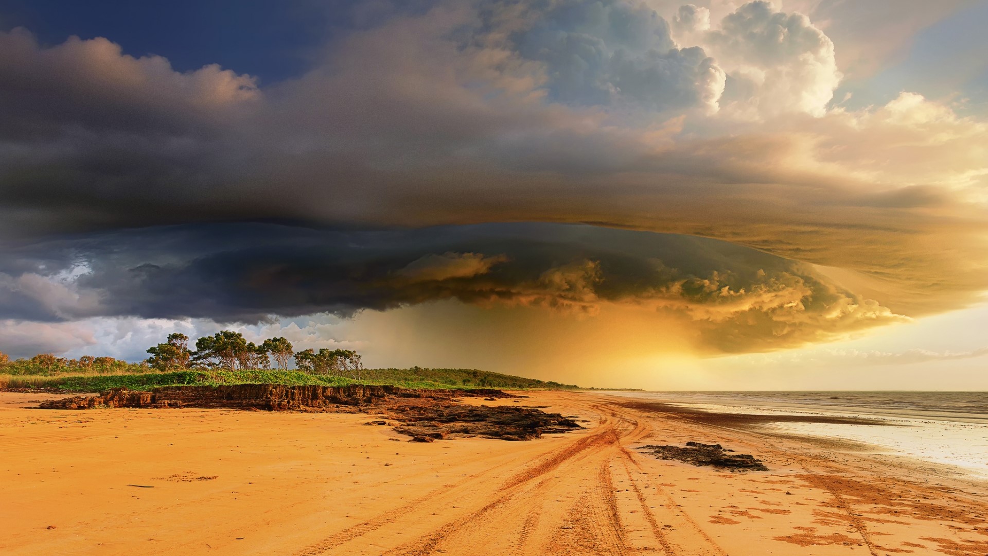 Storm clouds over a beach at sunset HD Wallpaper