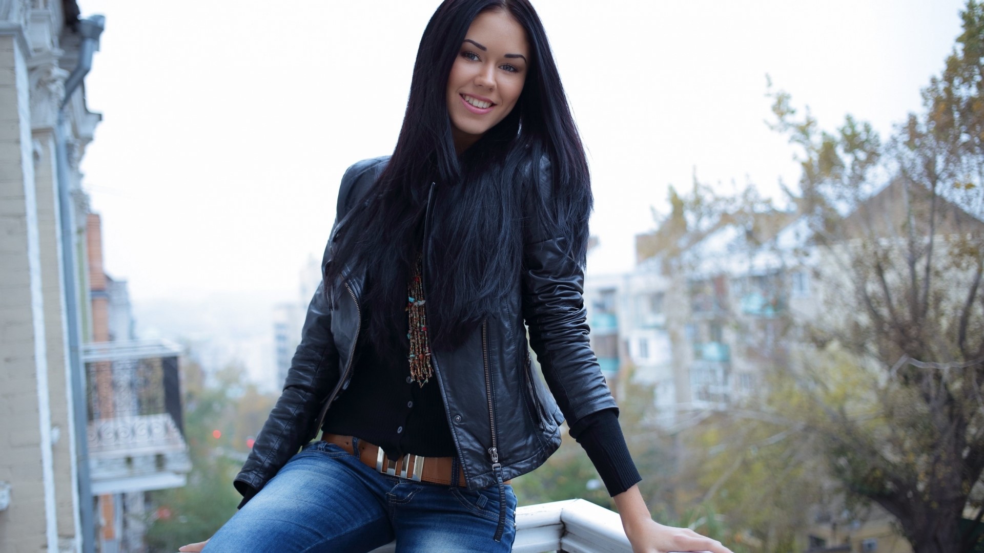 Young woman in leather jacket and jeans on balcony HD Wallpaper