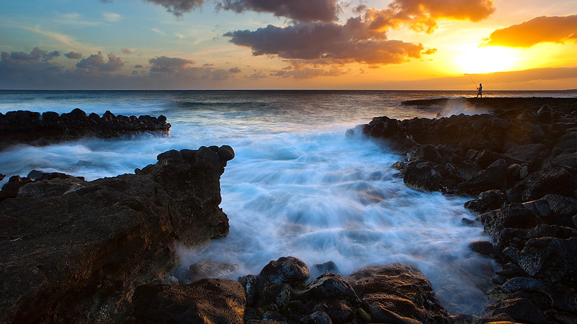 Fisherman on rocky shore at sunset HD Wallpaper