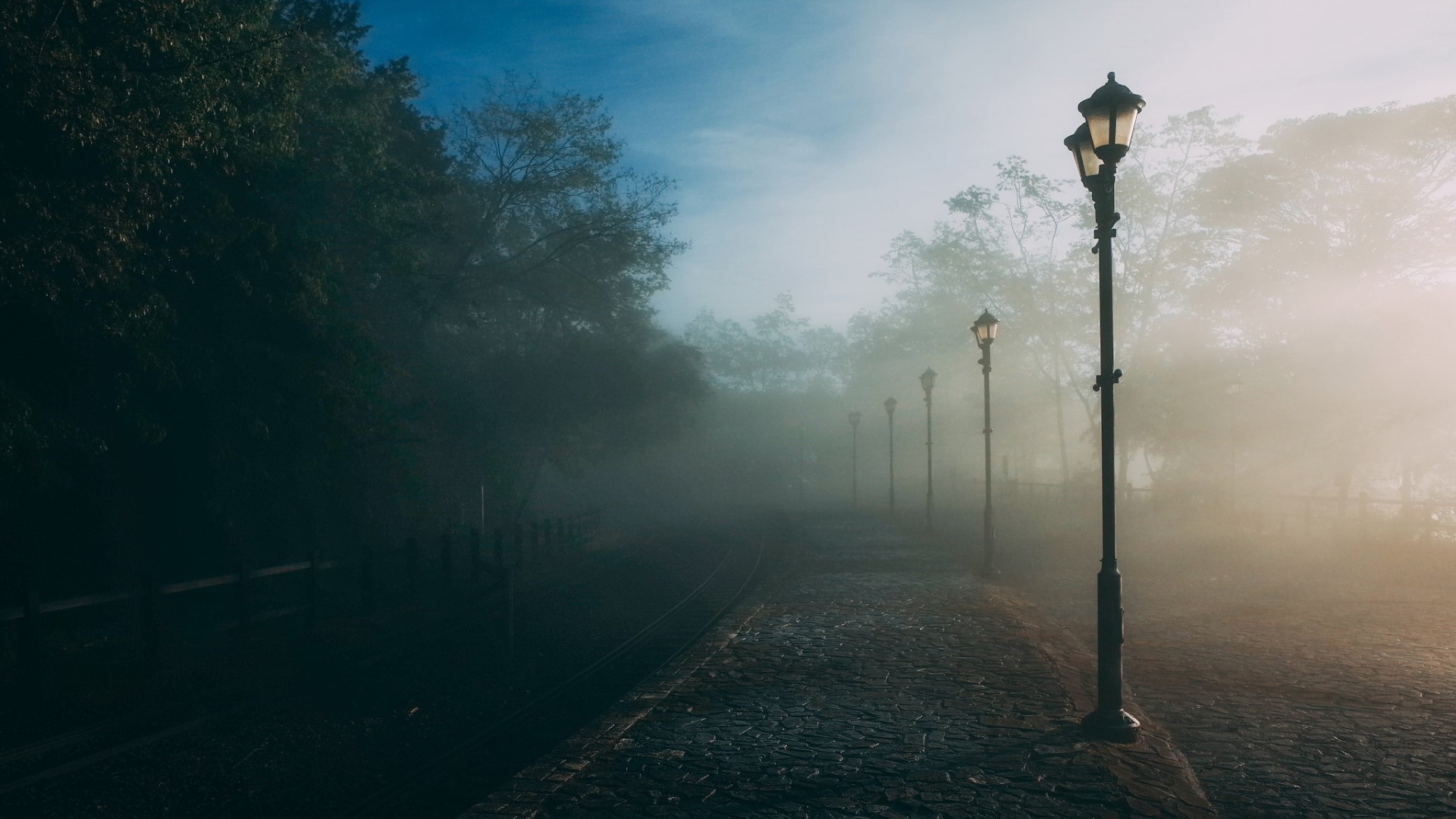 Foggy park path with lampposts at sunrise HD Wallpaper