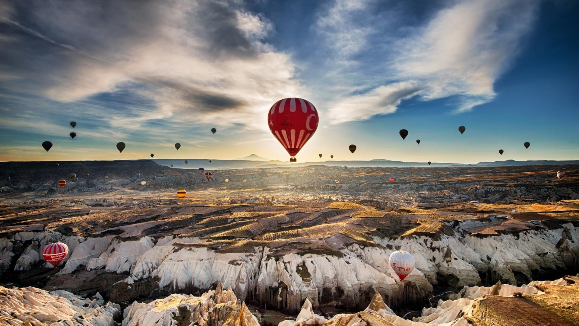 Hot air balloons over a rocky landscape at sunrise HD Wallpaper