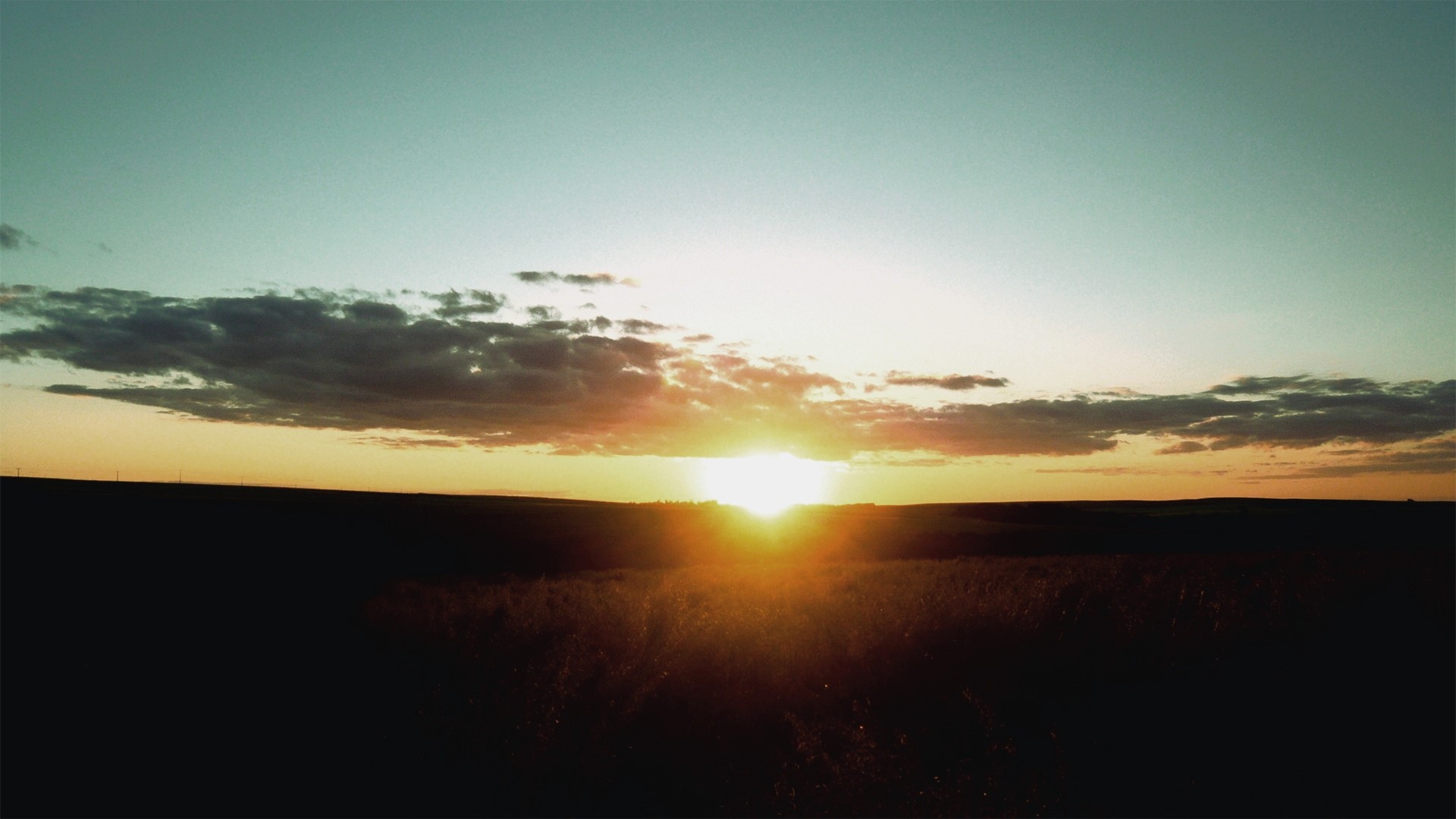 Sunset over a field with clouds HD Wallpaper