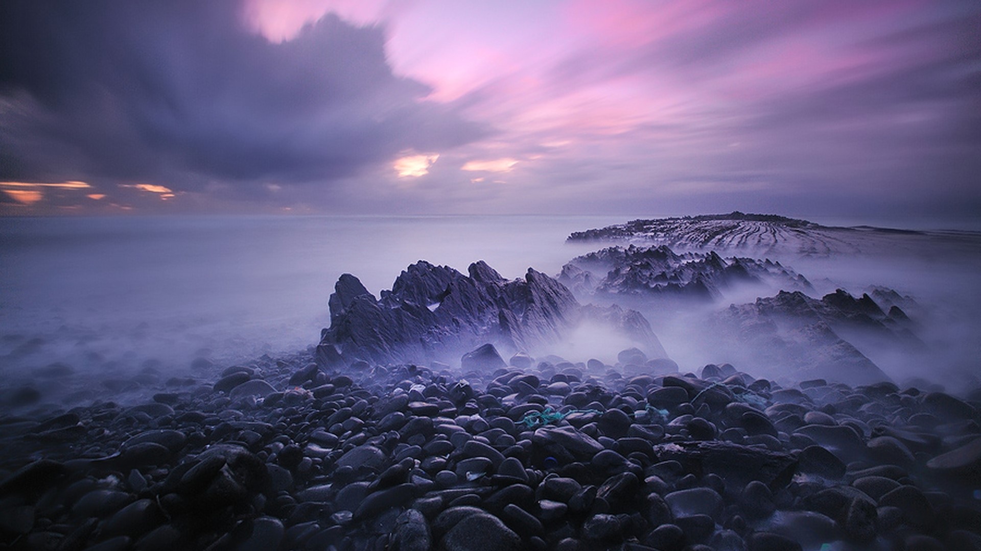 Rocky Shoreline with Purple Clouds at Dusk HD Wallpaper