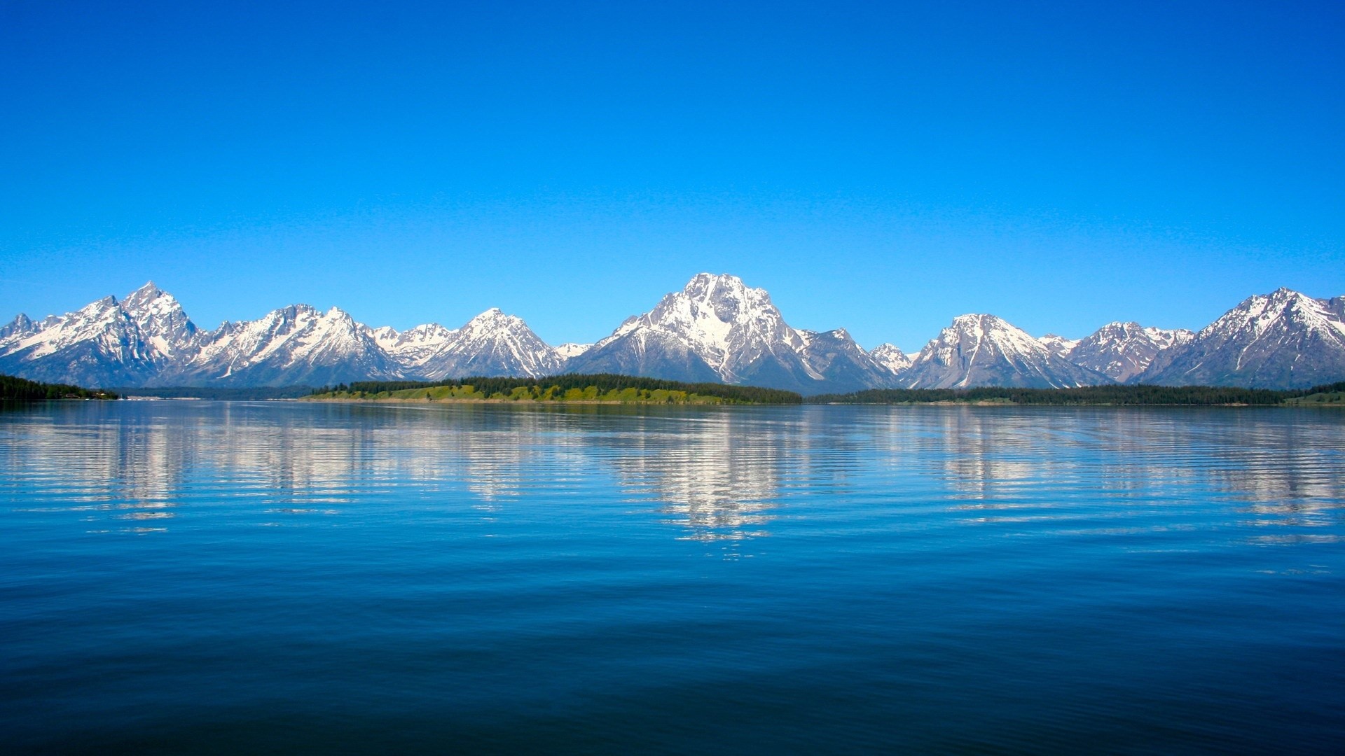 Snow-capped mountains reflected in a lake under a clear blue sky HD Wallpaper