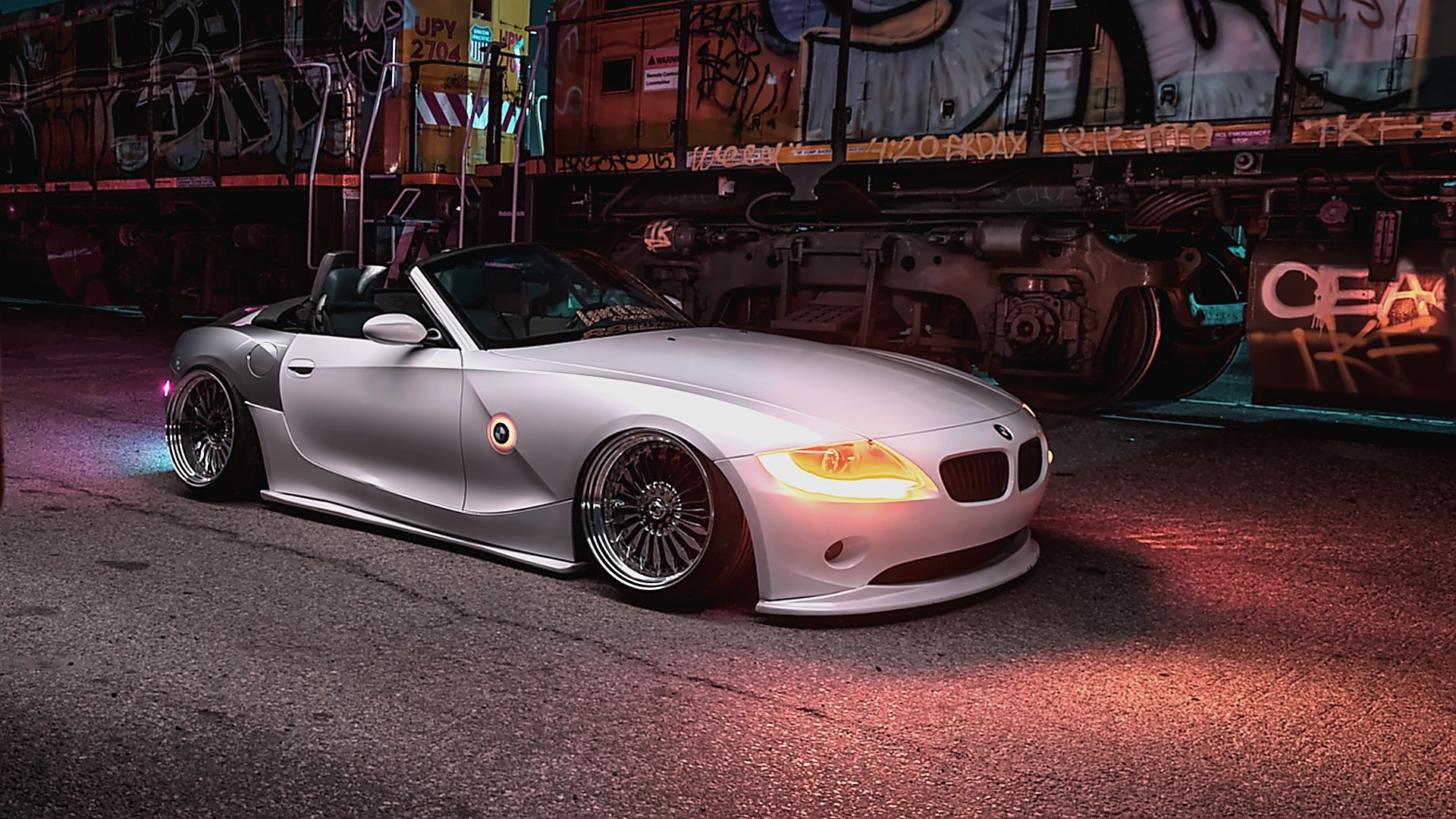 White BMW Z4 convertible parked next to graffiti-covered train HD Wallpaper