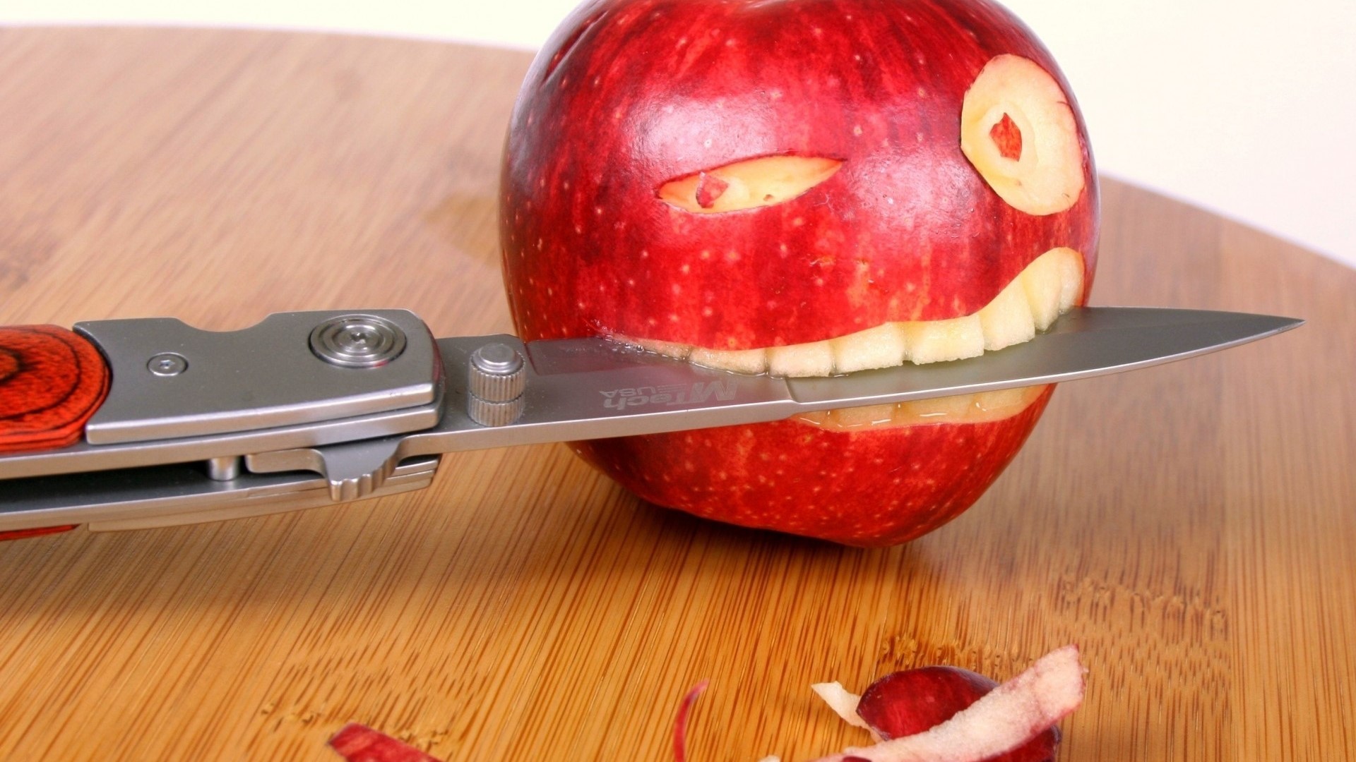 Knife cutting a carved apple on a wooden board HD Wallpaper