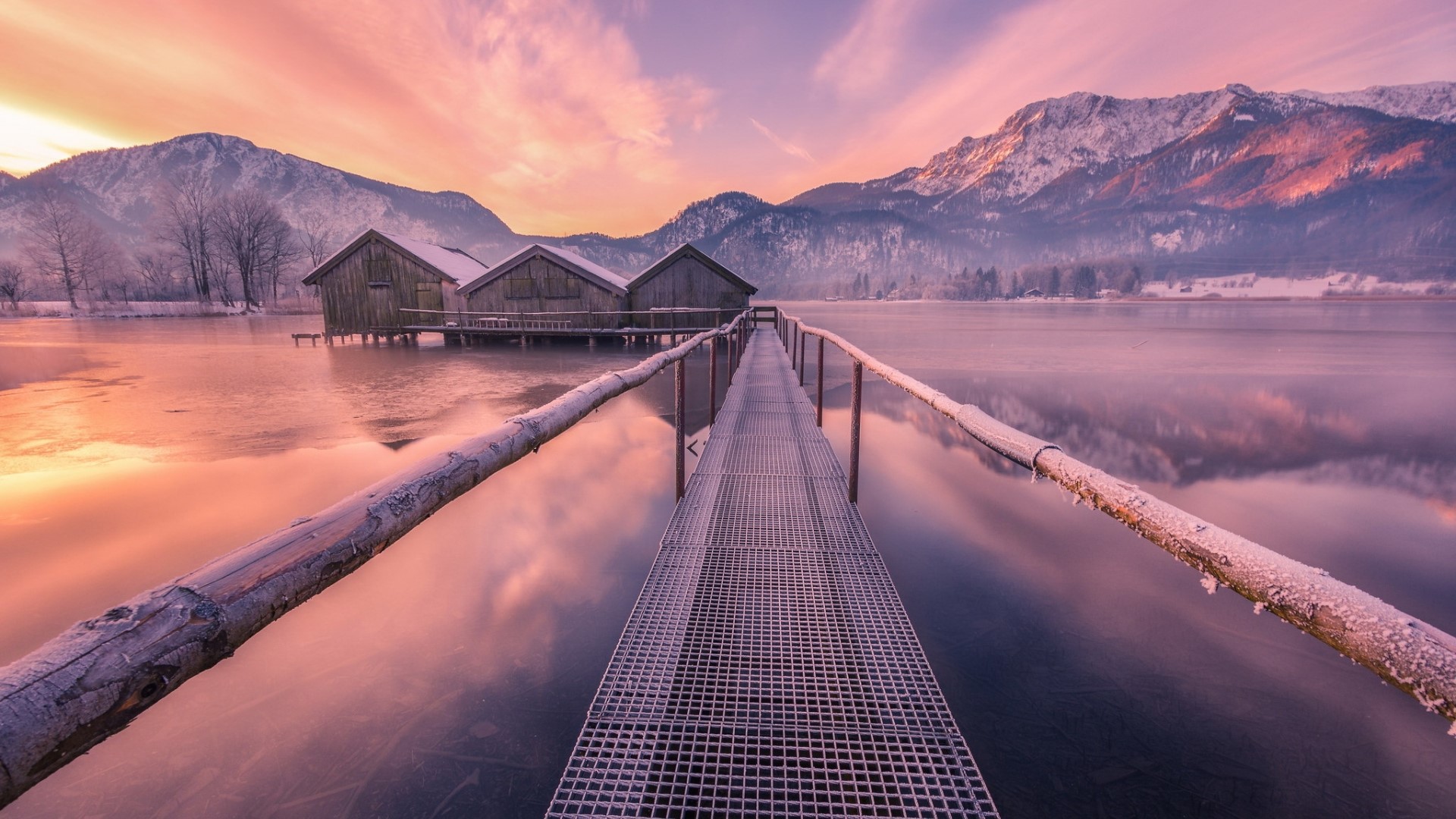 Wooden boathouses on a frozen lake with mountains at sunrise HD Wallpaper