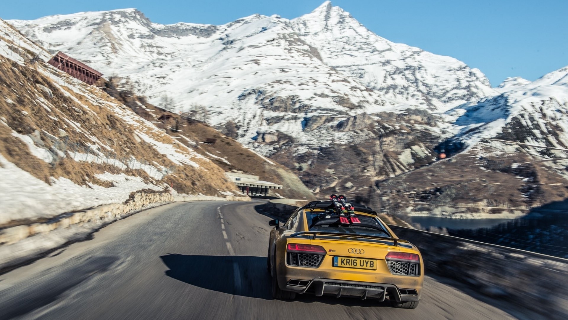 Yellow Audi R8 driving on a mountain road with skis HD Wallpaper