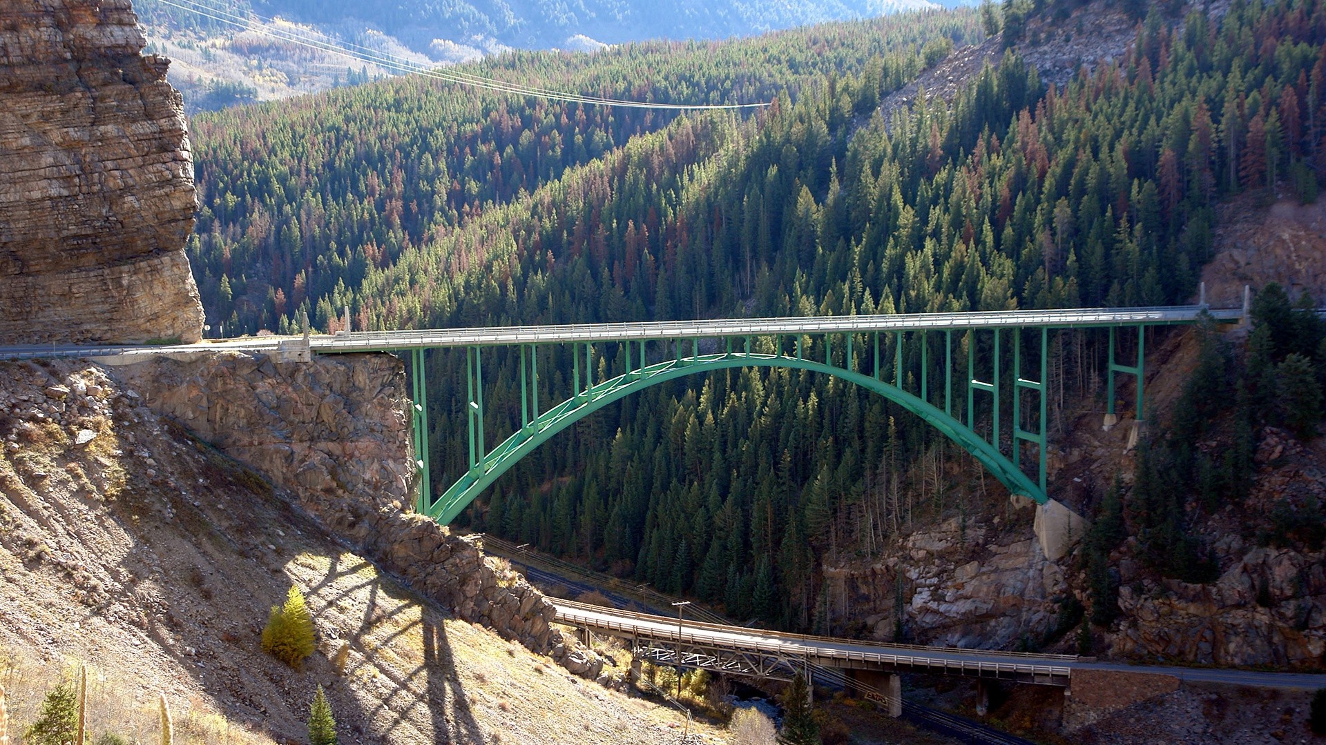 Red Cliff Bridge over a forested canyon HD Wallpaper