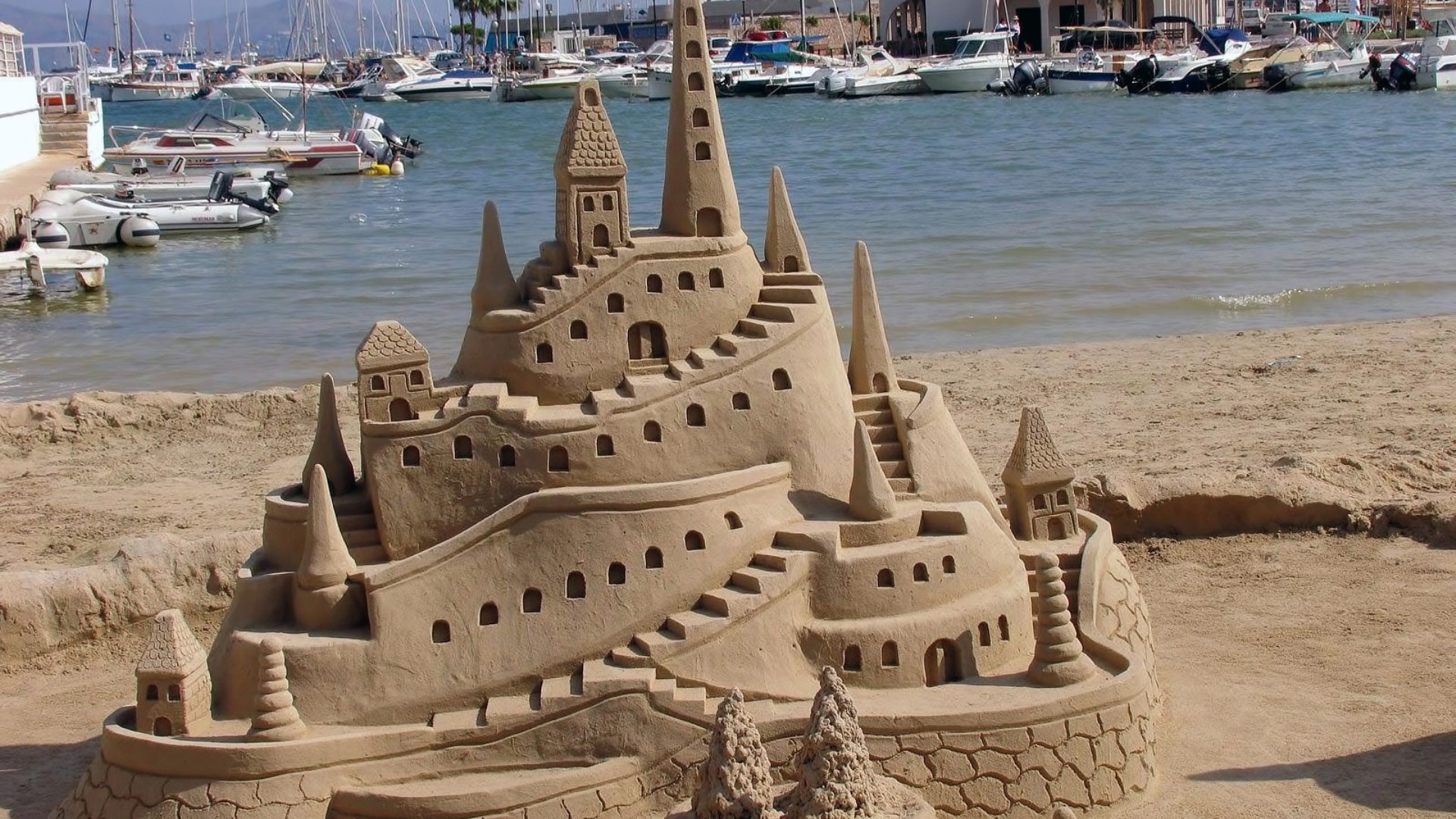Sand castle on a beach with boats in the background HD Wallpaper