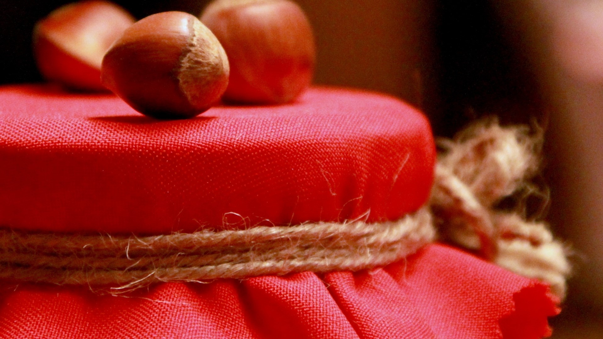 Jar lid covered in red fabric with hazelnuts HD Wallpaper