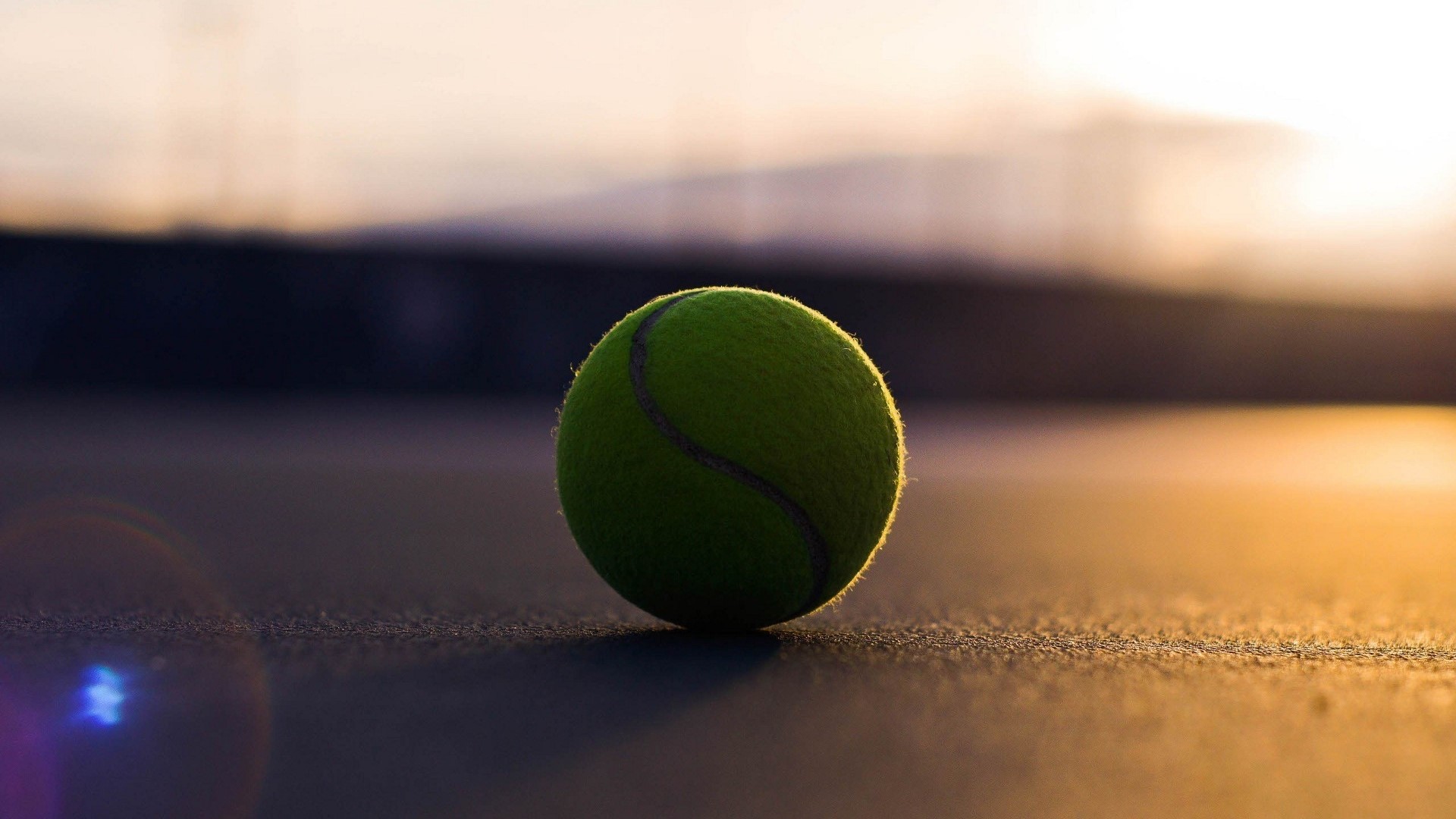 Tennis ball on a court at sunset HD Wallpaper