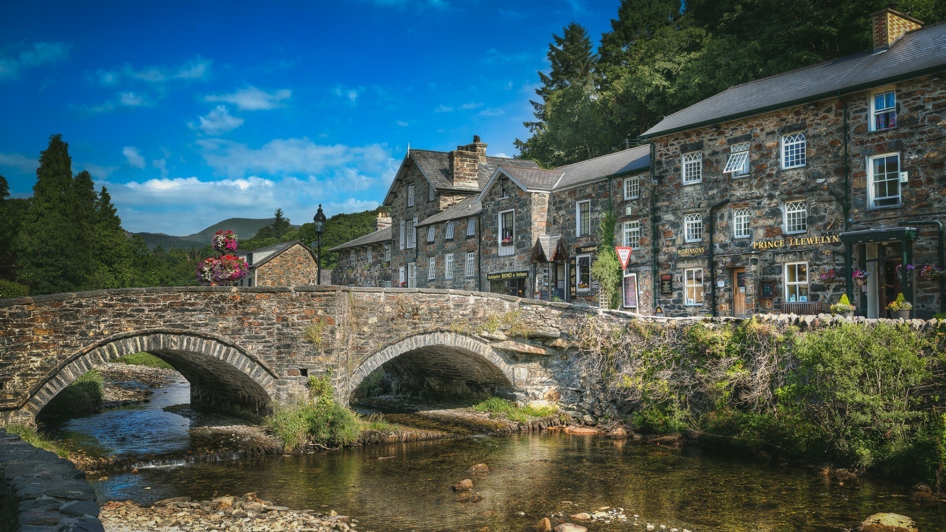 Stone bridge over a river with stone buildings in Wales HD Wallpaper