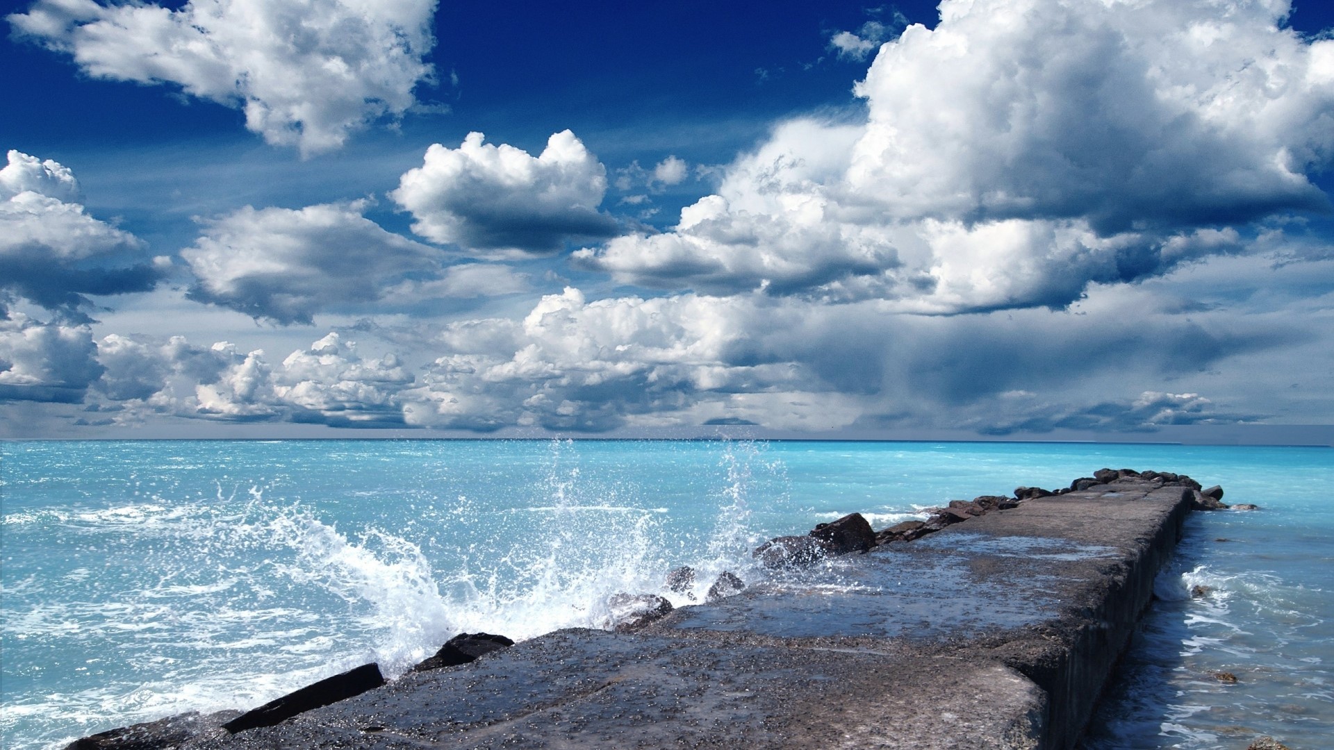 Stone dock on a bright blue sea under a cloudy sky HD Wallpaper
