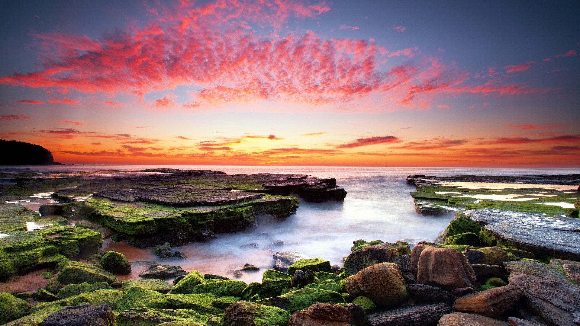 Ocean sunset with red clouds and mossy rocks HD Wallpaper