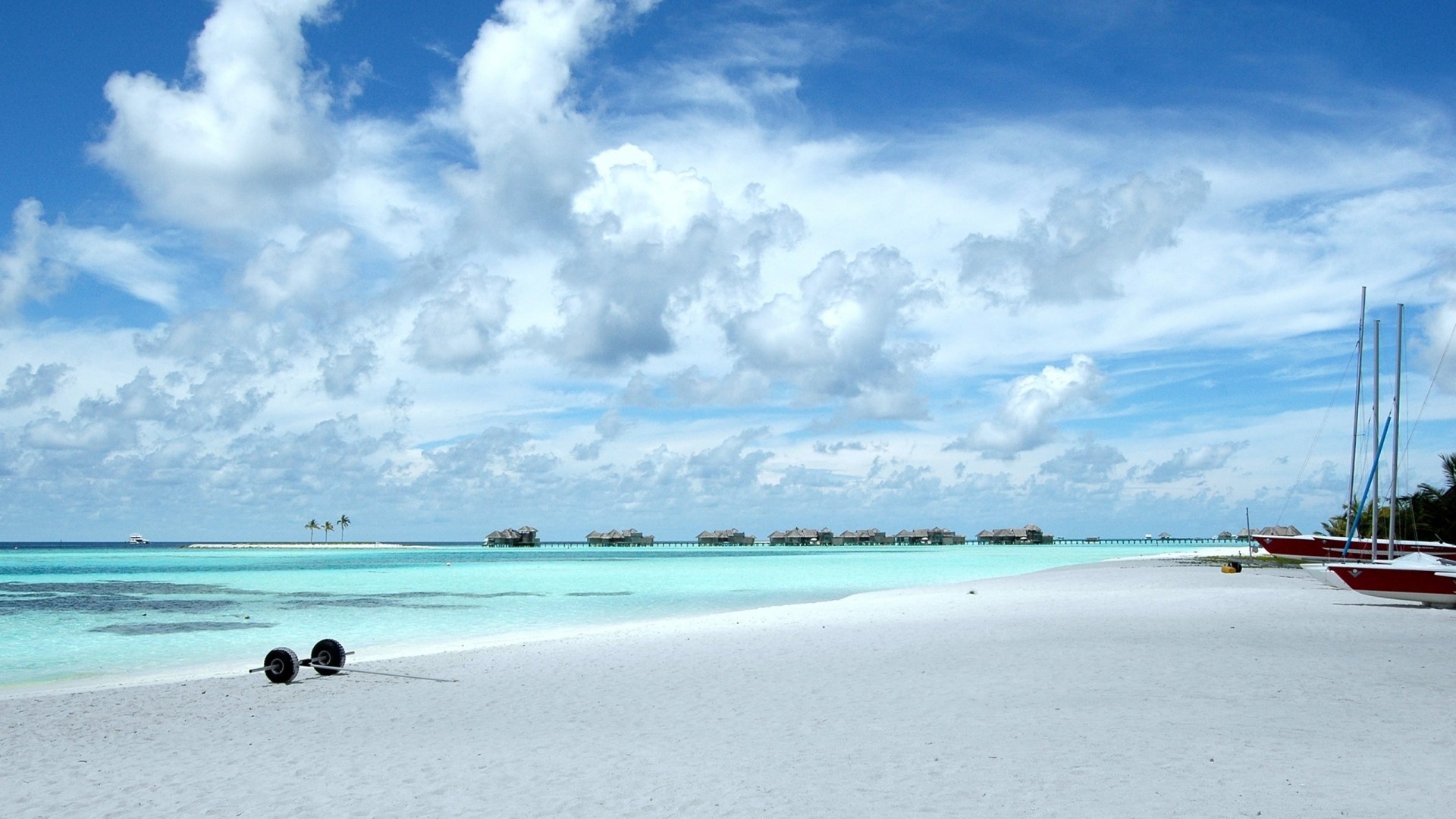 Sailboats on a white sand beach with overwater bungalows HD Wallpaper