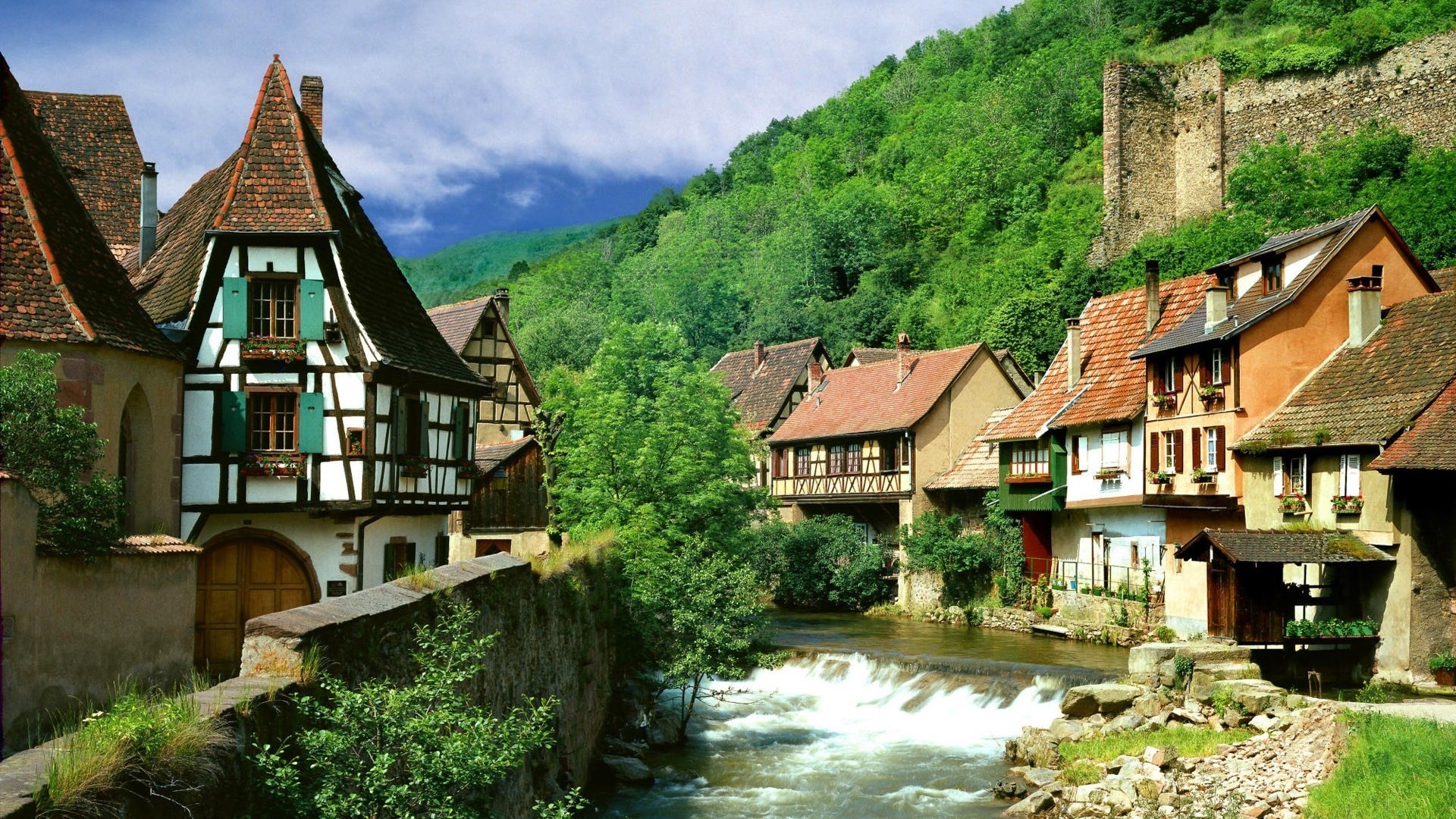 Half-timbered houses along a river in a mountain village HD Wallpaper