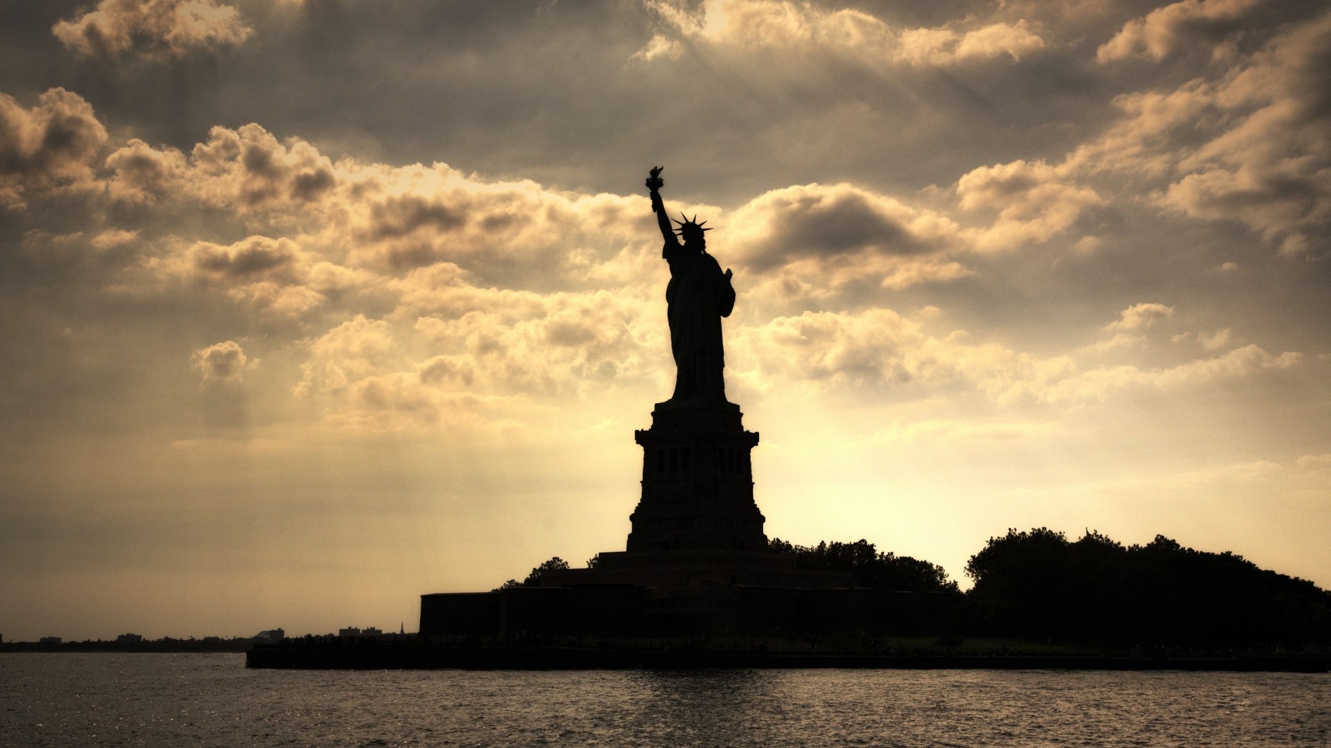 Statue of Liberty silhouetted against cloudy sky HD Wallpaper