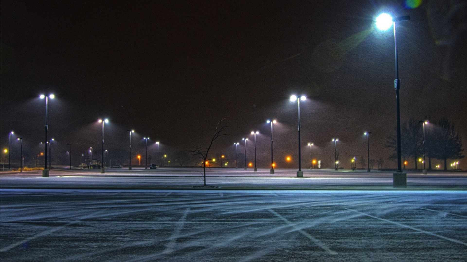 Snowy parking lot at night with streetlights HD Wallpaper