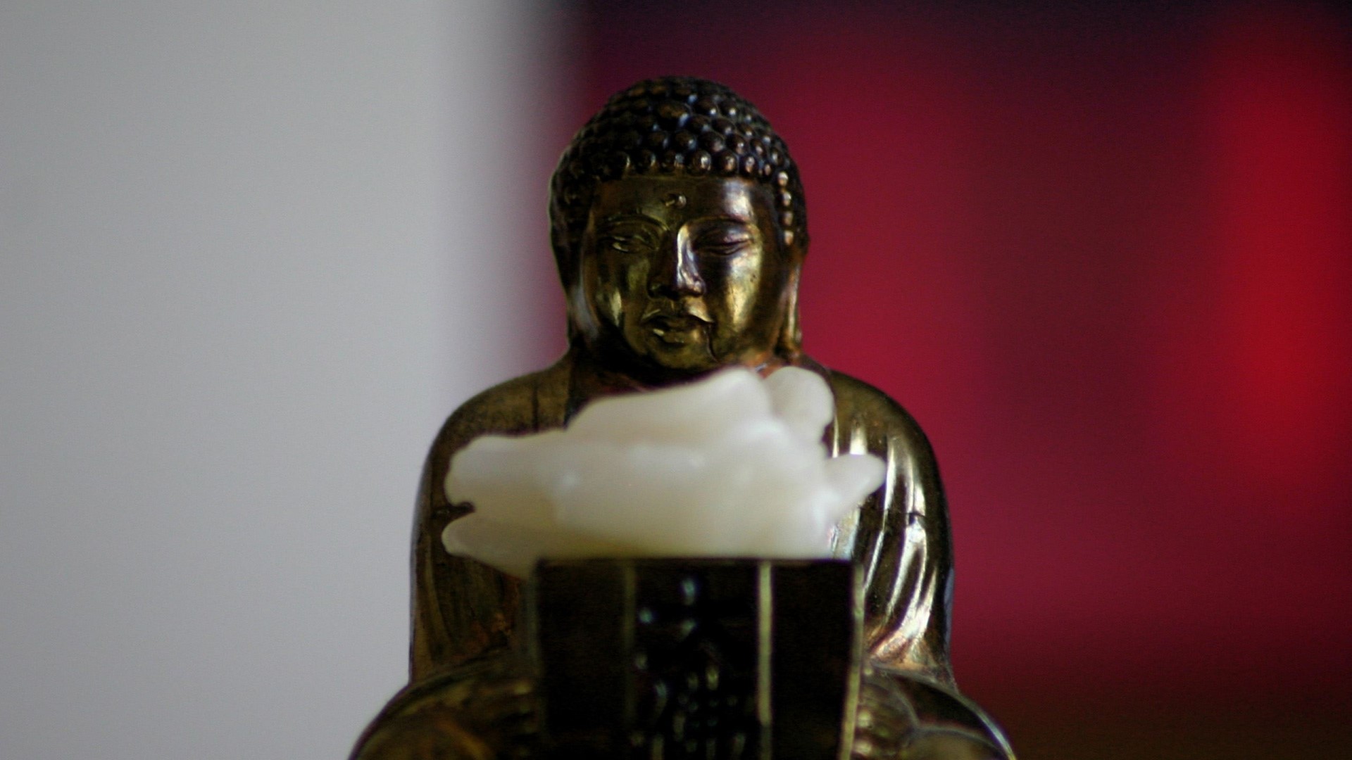 Small Buddha statue holding a white object HD Wallpaper