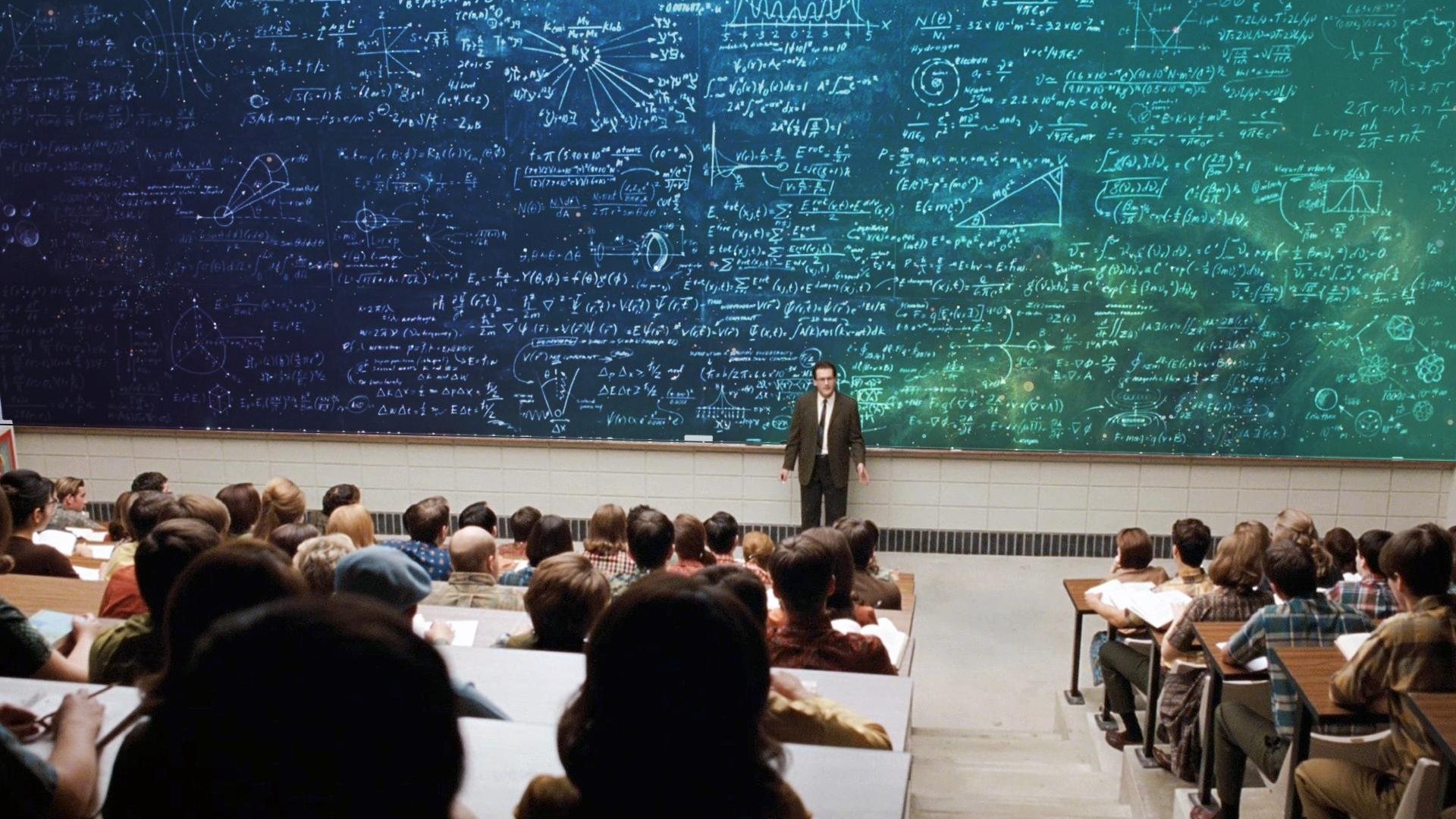 A professor stands before a blackboard filled with equations in a classroom. HD Wallpaper