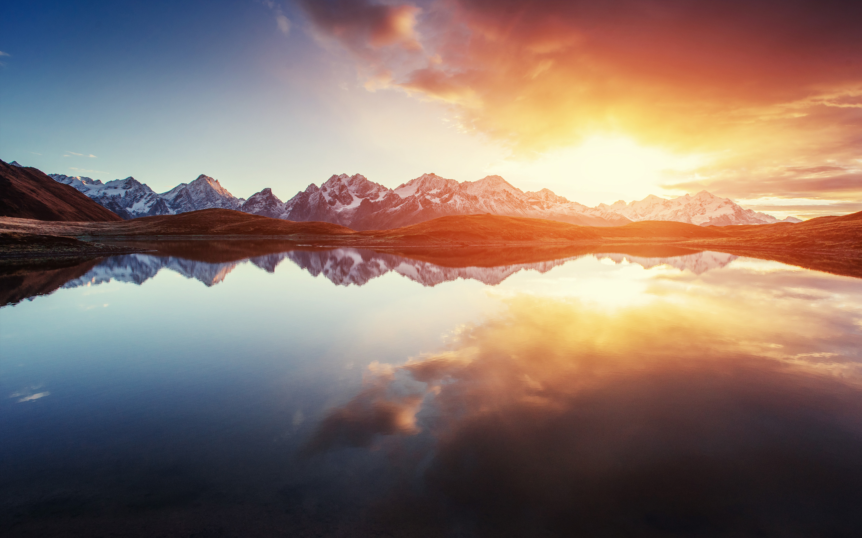 Snow-capped mountains reflected in a lake at sunrise HD Wallpaper