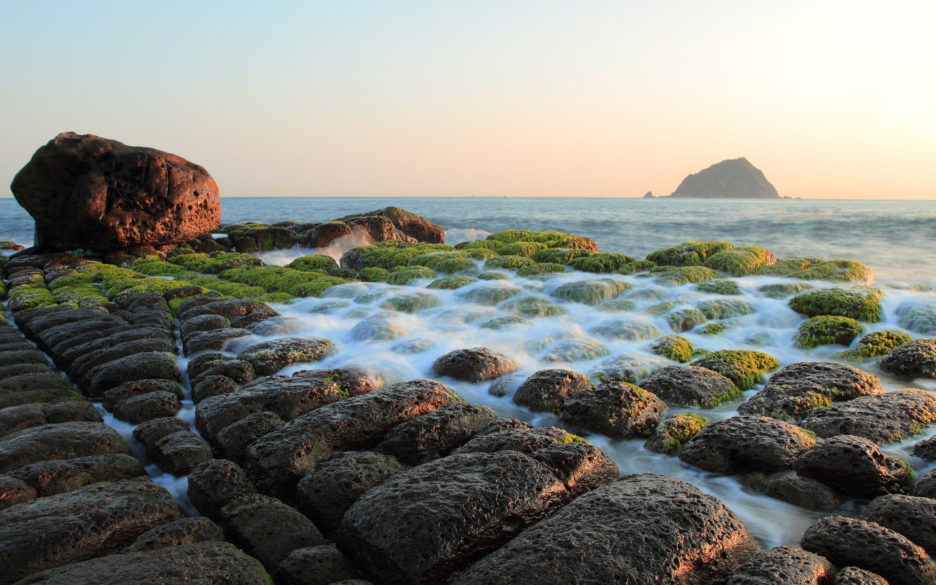 Rocky coastline with moss-covered rocks and ocean waves HD Wallpaper