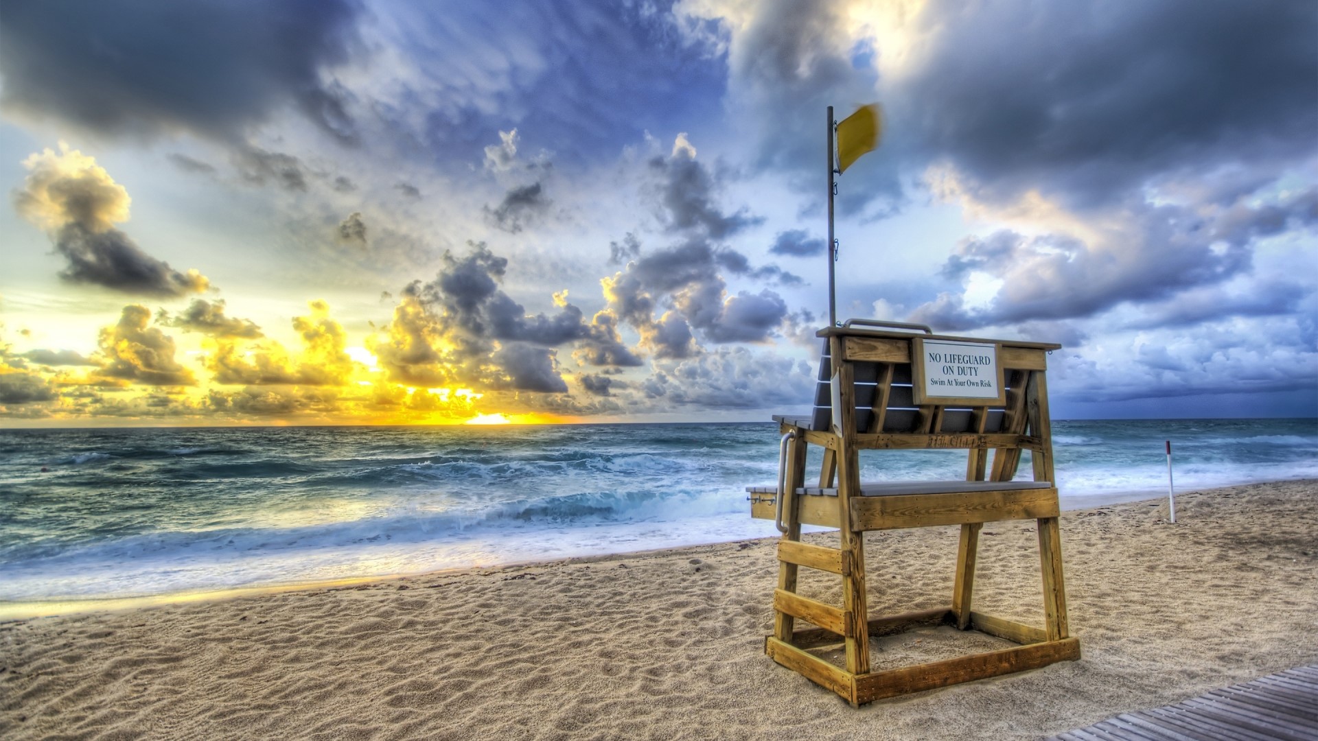 Lifeguard tower with yellow flag on beach at sunrise HD Wallpaper