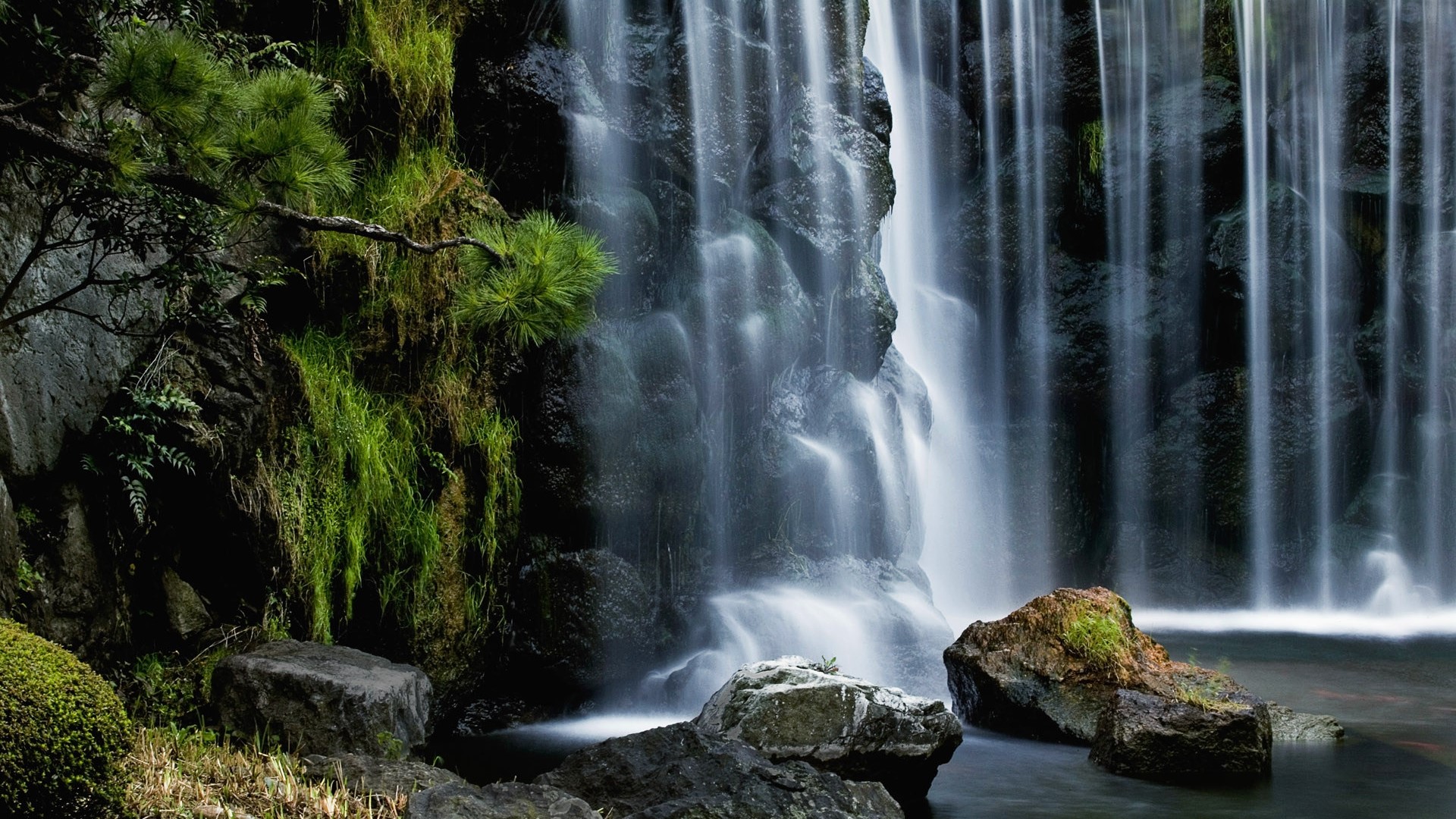Waterfall cascading over mossy rocks HD Wallpaper