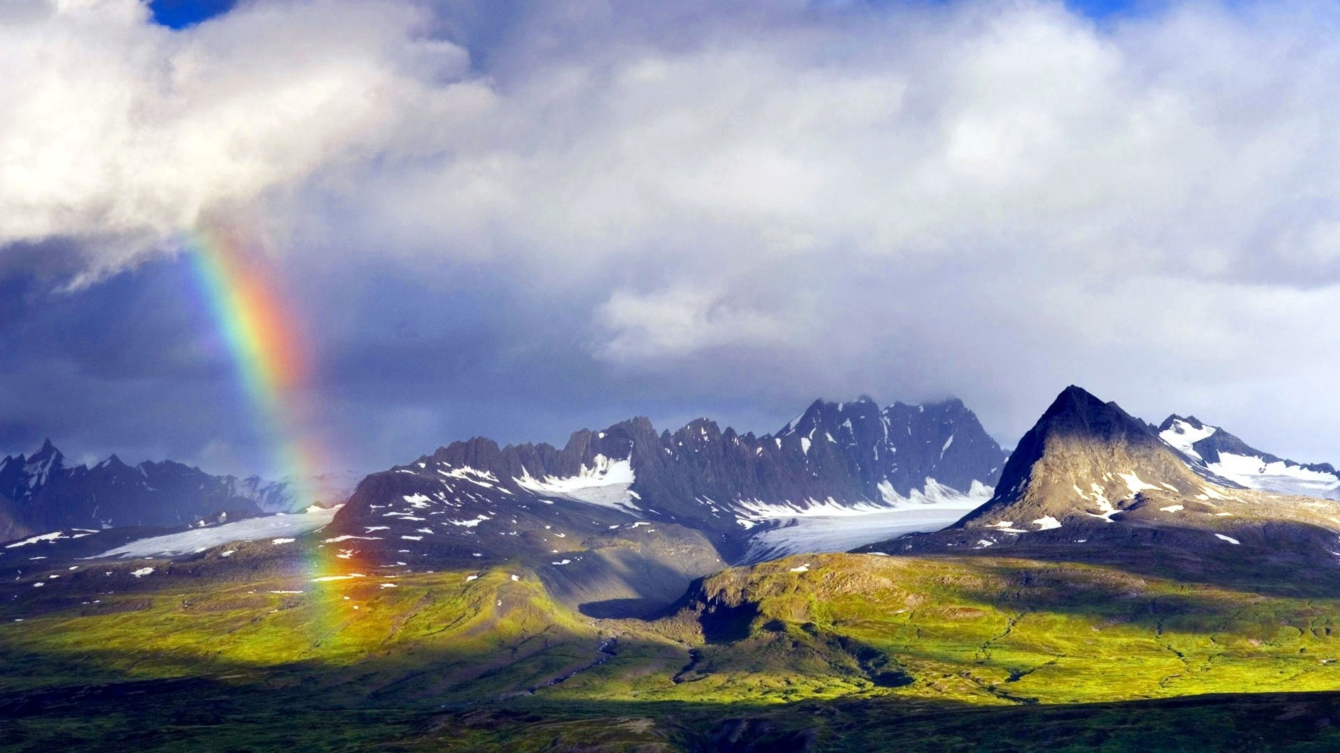 Rainbow over snow-capped mountains and green hills HD Wallpaper