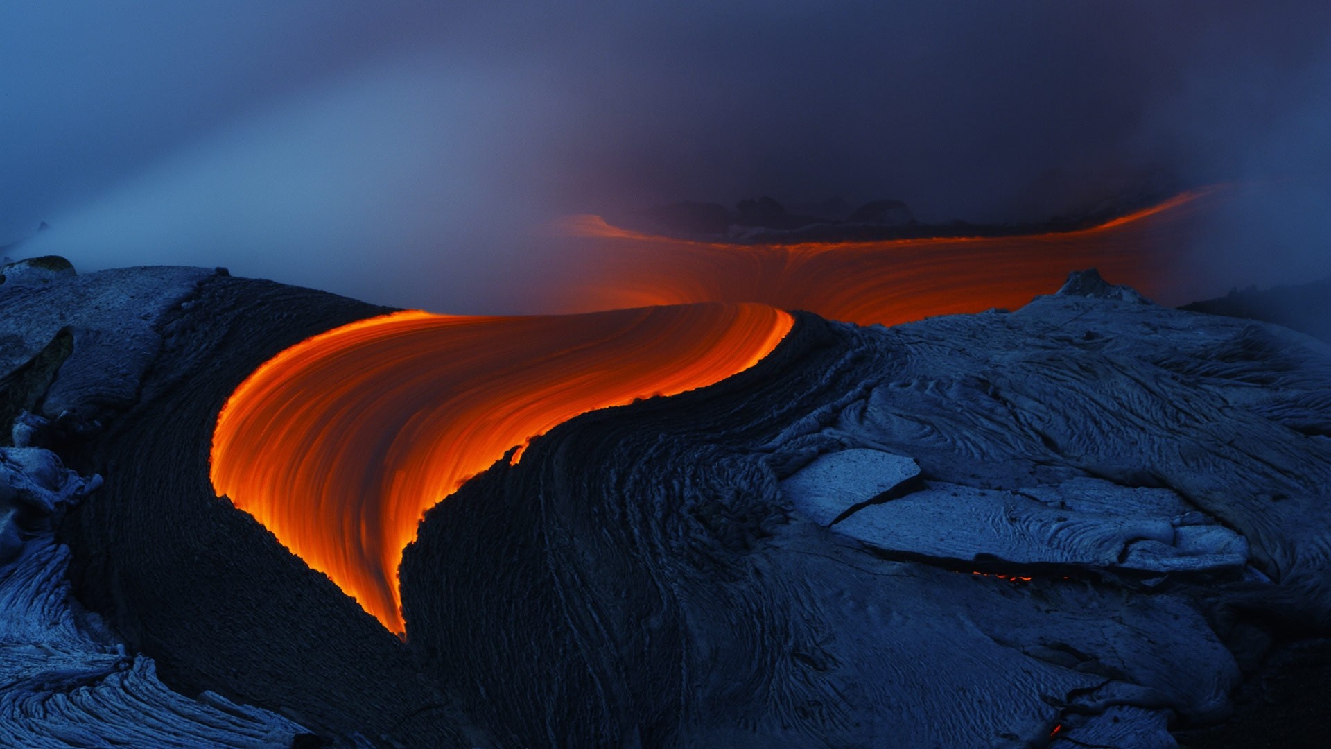 Molten lava flowing over dark volcanic rock HD Wallpaper