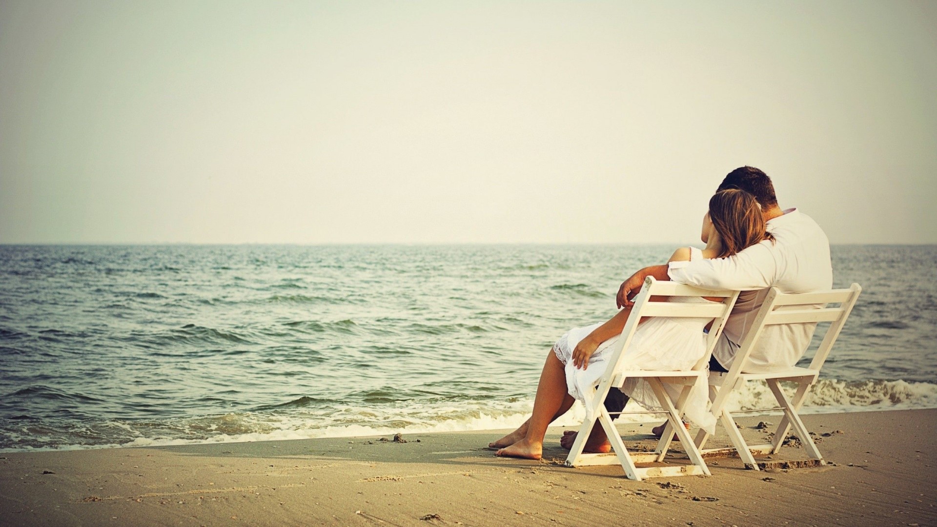 Couple sitting on chairs at the beach HD Wallpaper