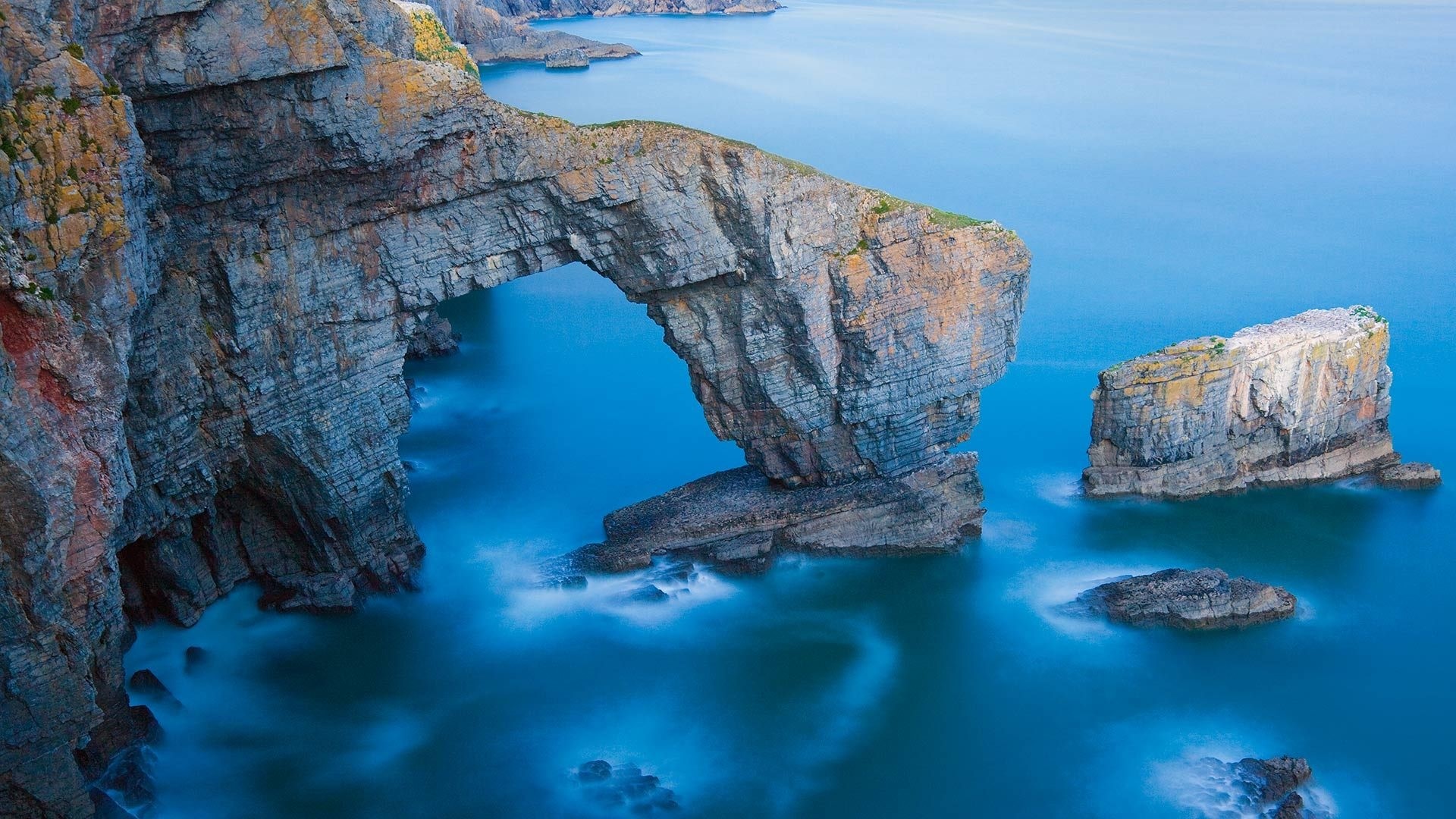 Natural rock arch over blue ocean water HD Wallpaper