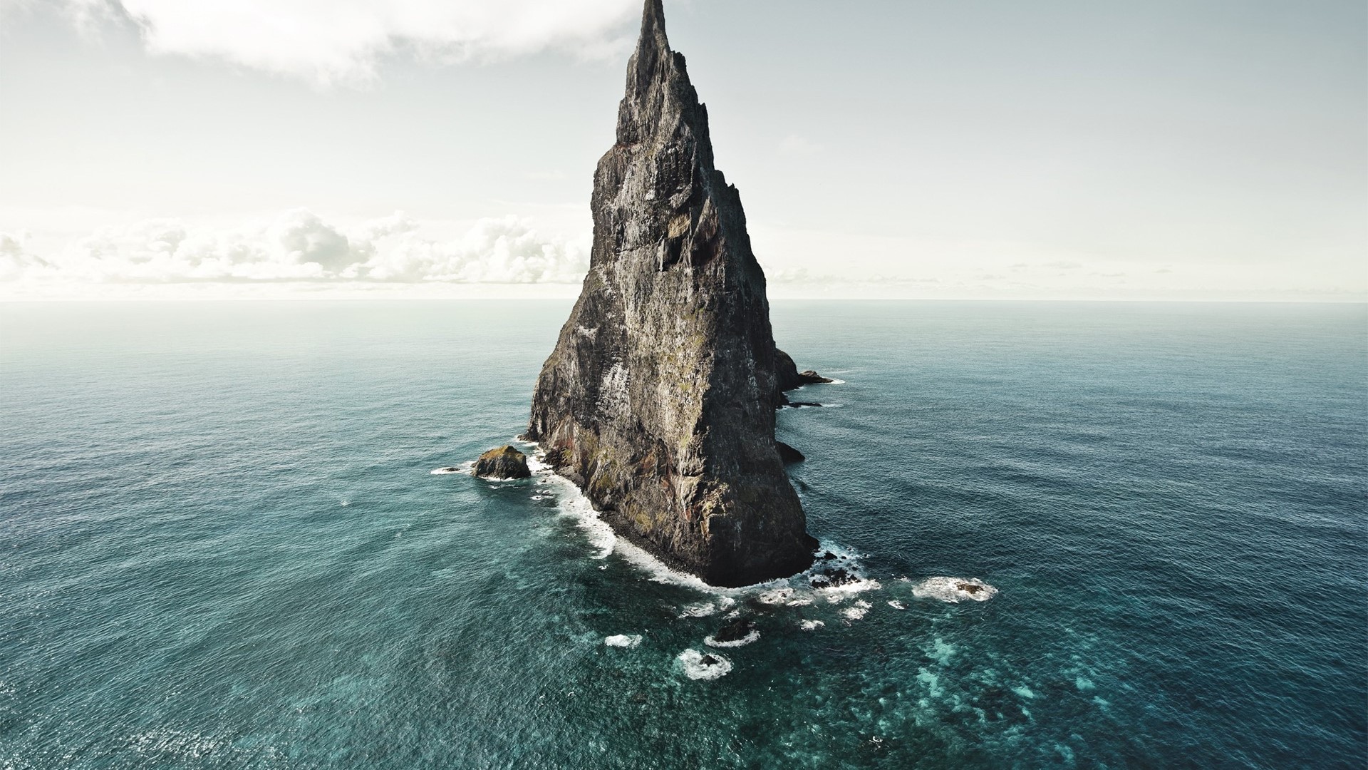 Tall rock formation in the ocean HD Wallpaper