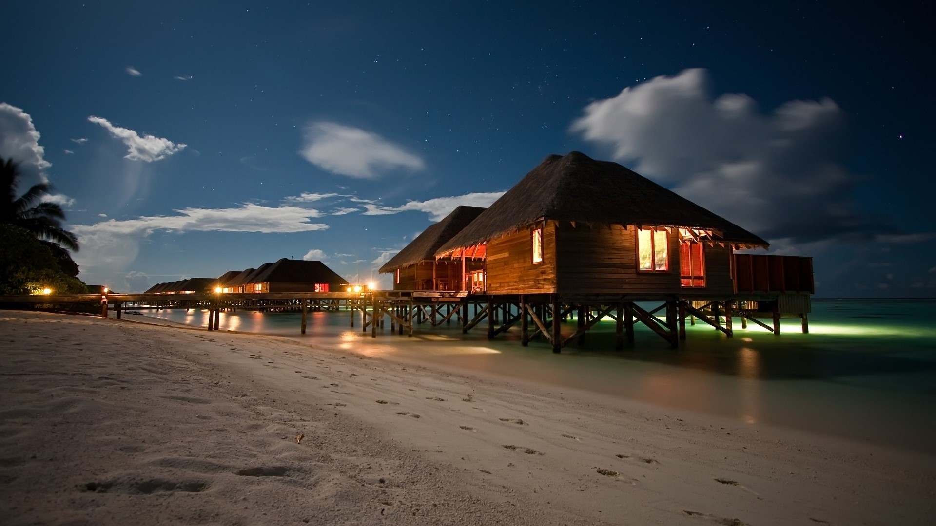Beach bungalows on stilts at night HD Wallpaper