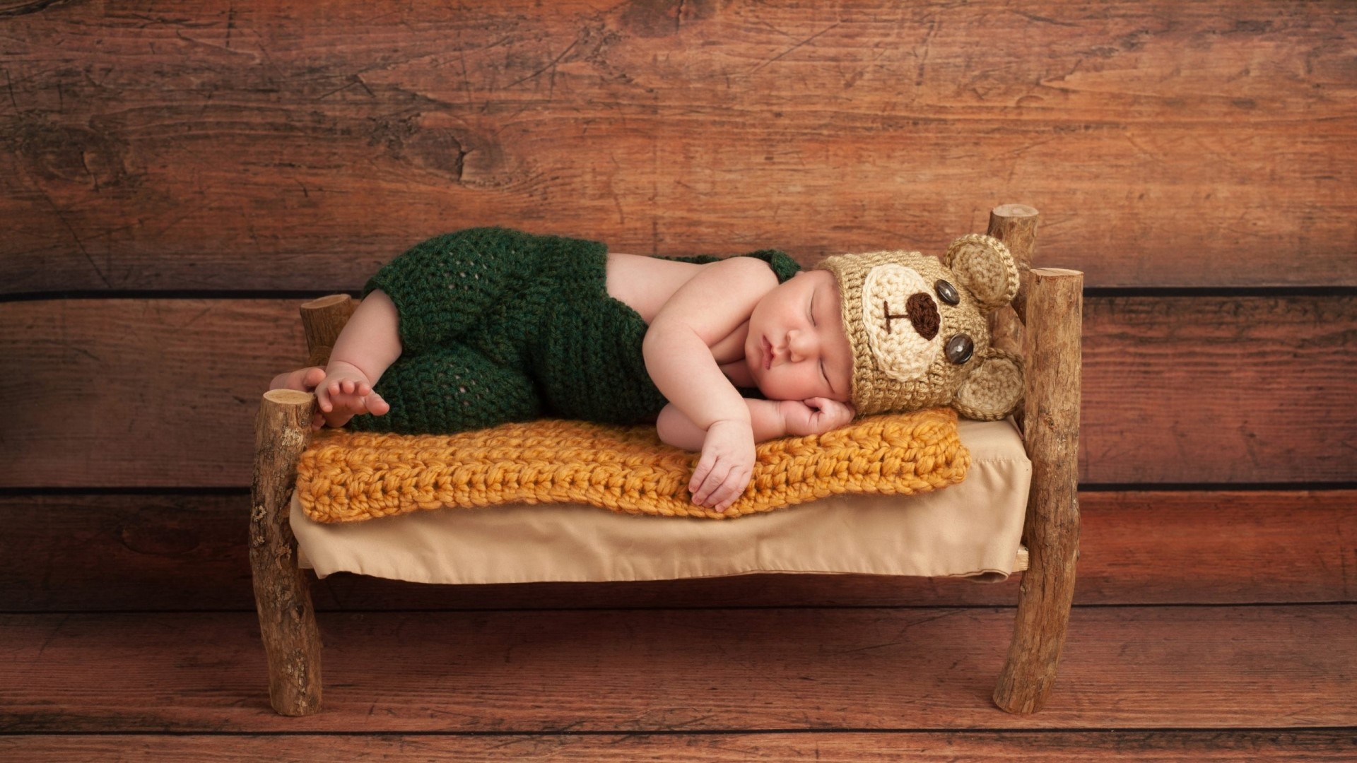 Newborn baby sleeping in a bear costume on a bed HD Wallpaper