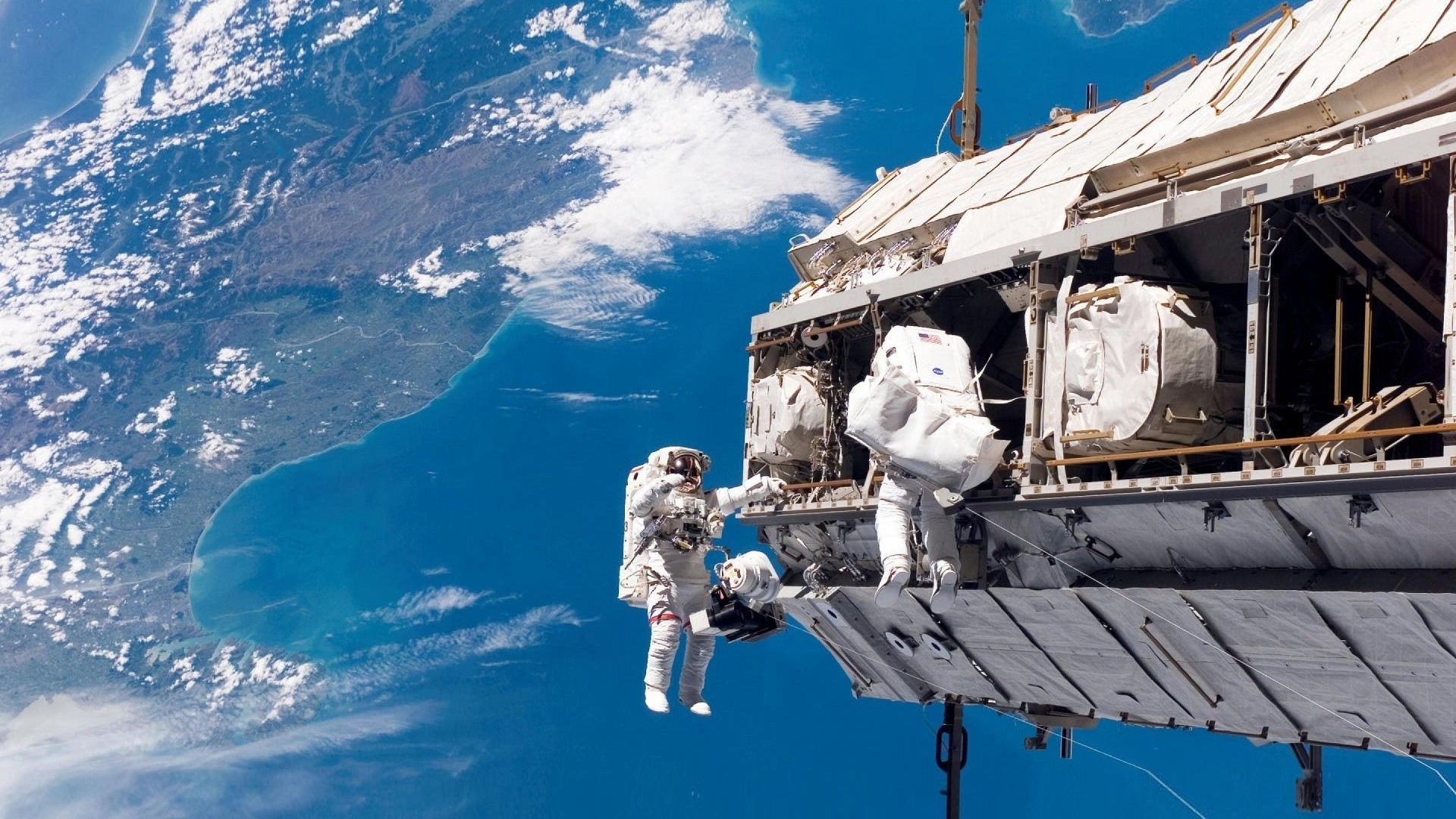 Astronauts performing a spacewalk outside the International Space Station HD Wallpaper