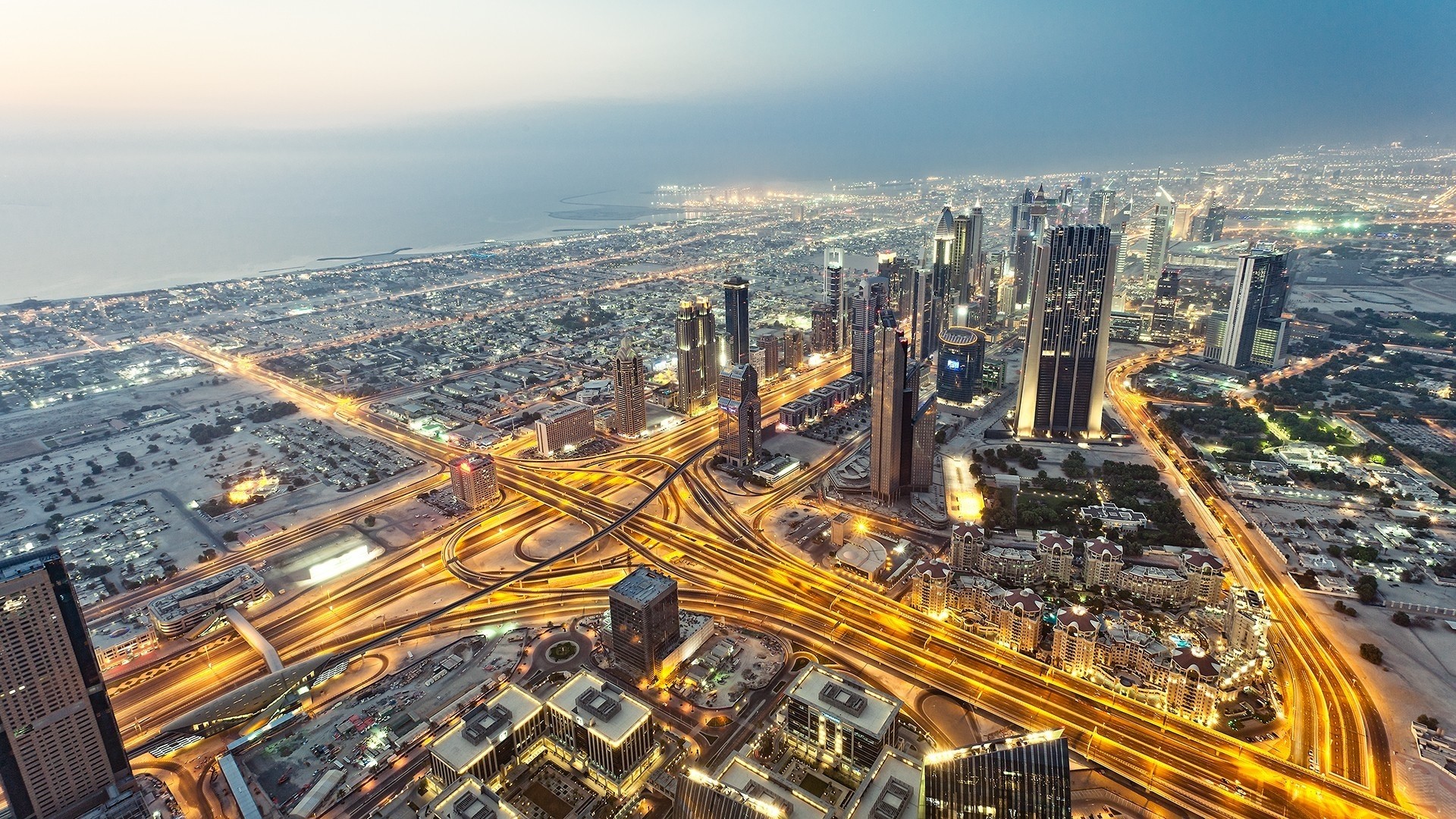 Aerial view of Dubai cityscape at night with illuminated highways HD Wallpaper