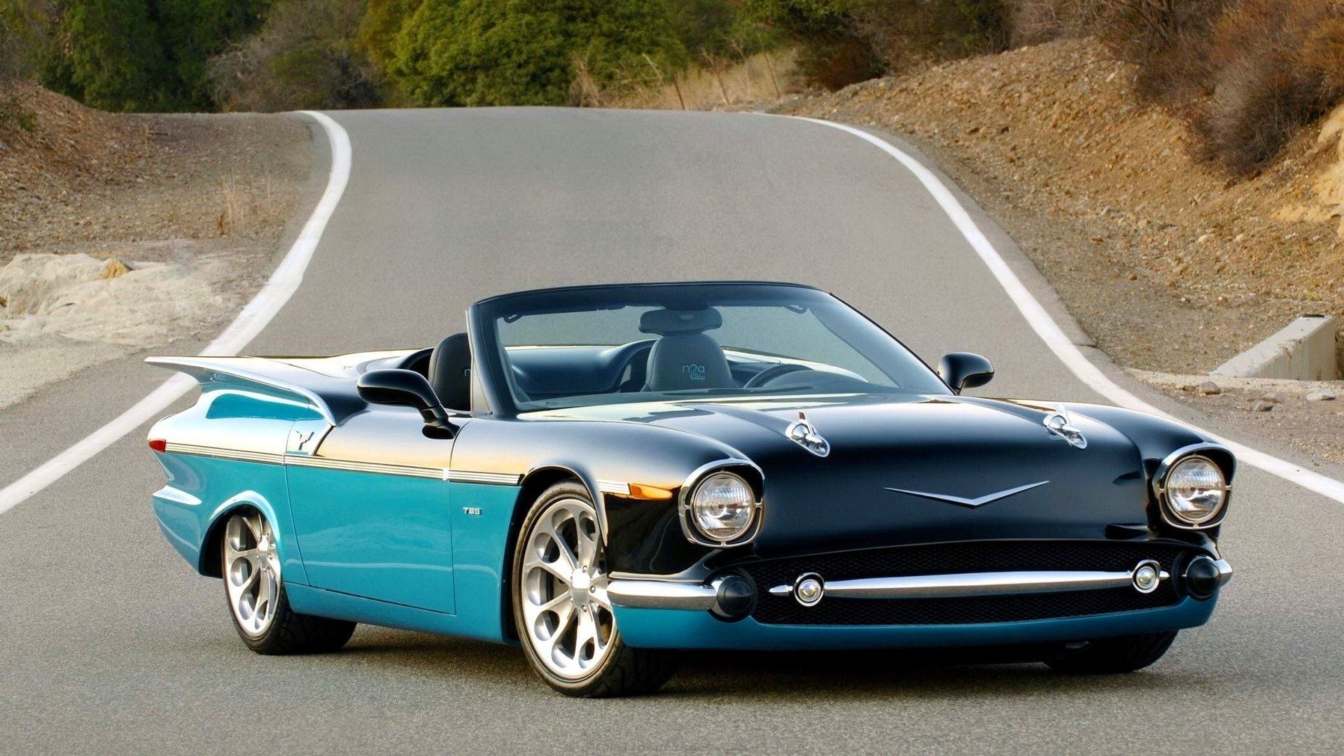 Custom two-tone blue and black convertible classic car on a winding road HD Wallpaper